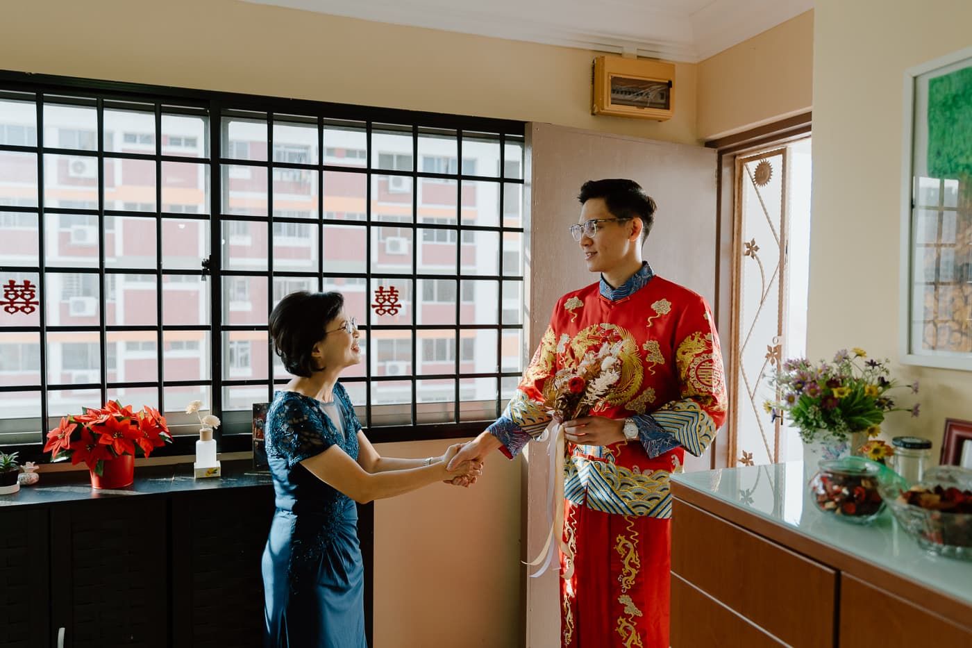 Traditional Chinese wedding ceremony with couple exchanging gifts in interior room.