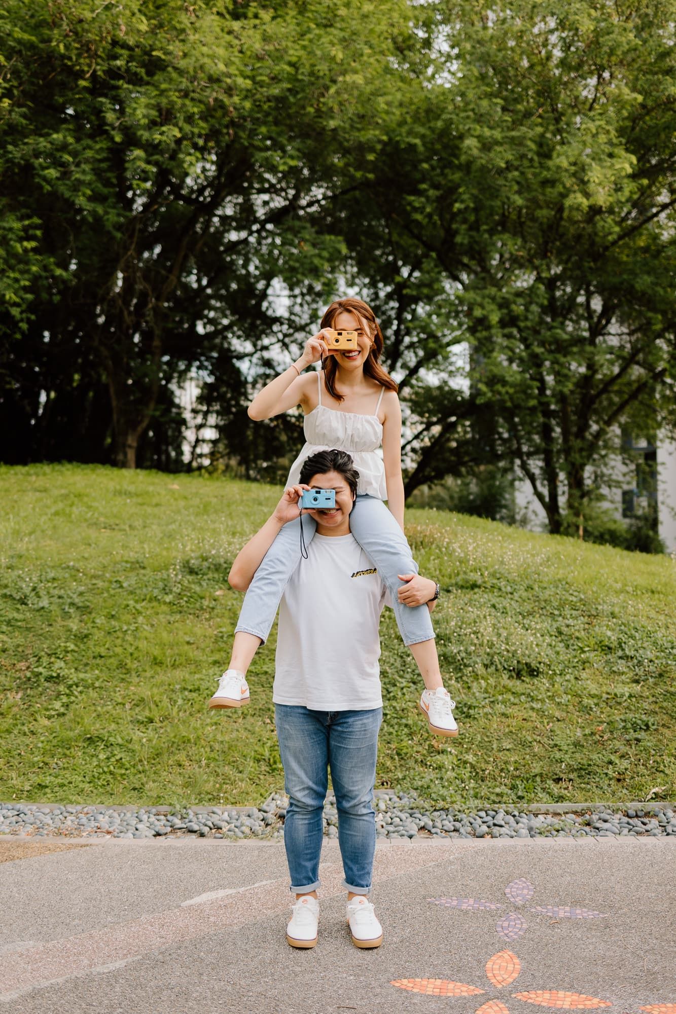 Playful outdoor photo of two people with sunglasses having fun in park setting.