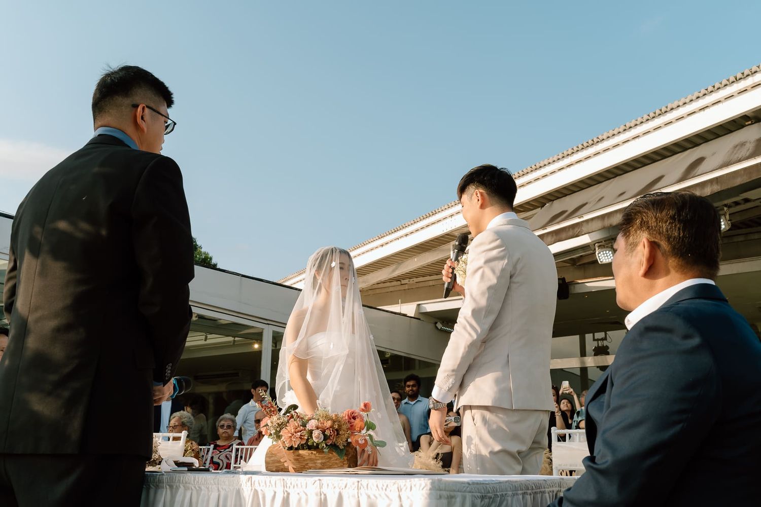 An outdoor wedding ceremony in progress with an officiant and couple at a decorated altar.