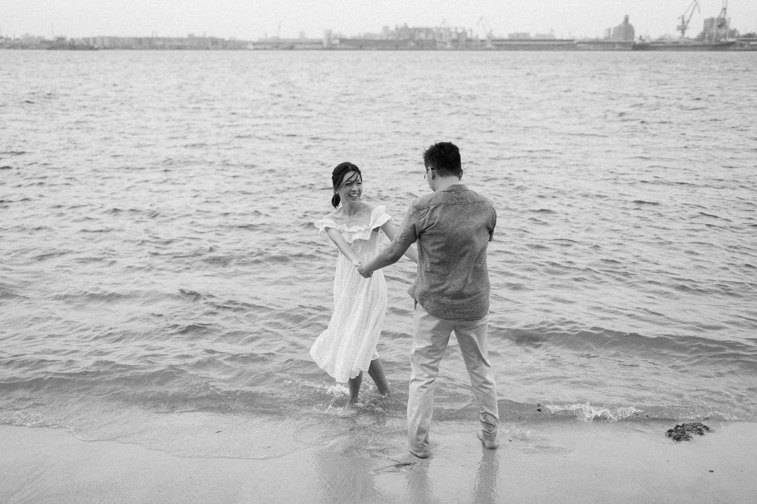 A playful couple dancing in the shallow waters of a beach.