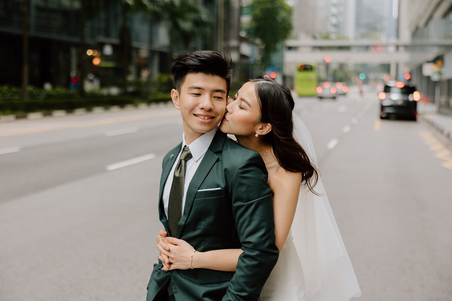 A tender moment between newlyweds on a modern city street with tall buildings.