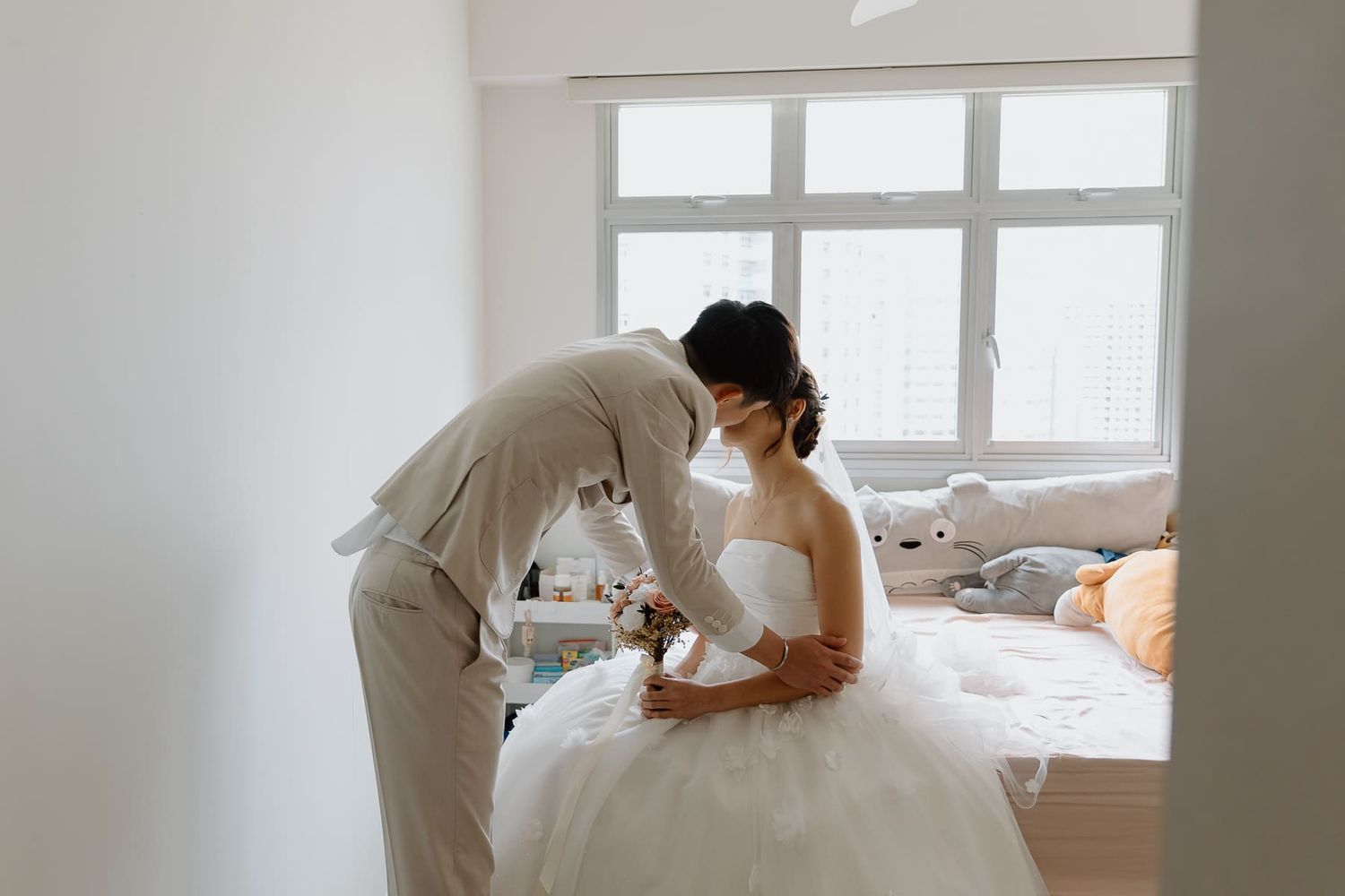 Intimate wedding moment captured in bright sunlit room with white decor.