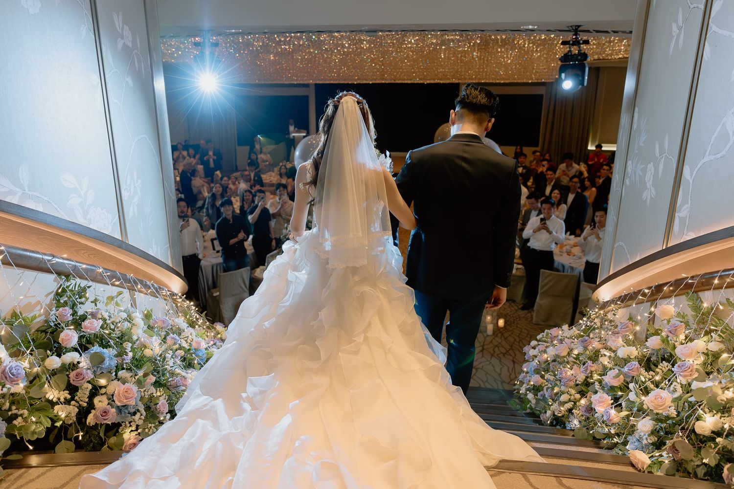 Elegant wedding ballroom decorated with white floral arrangements and twinkling lights.
