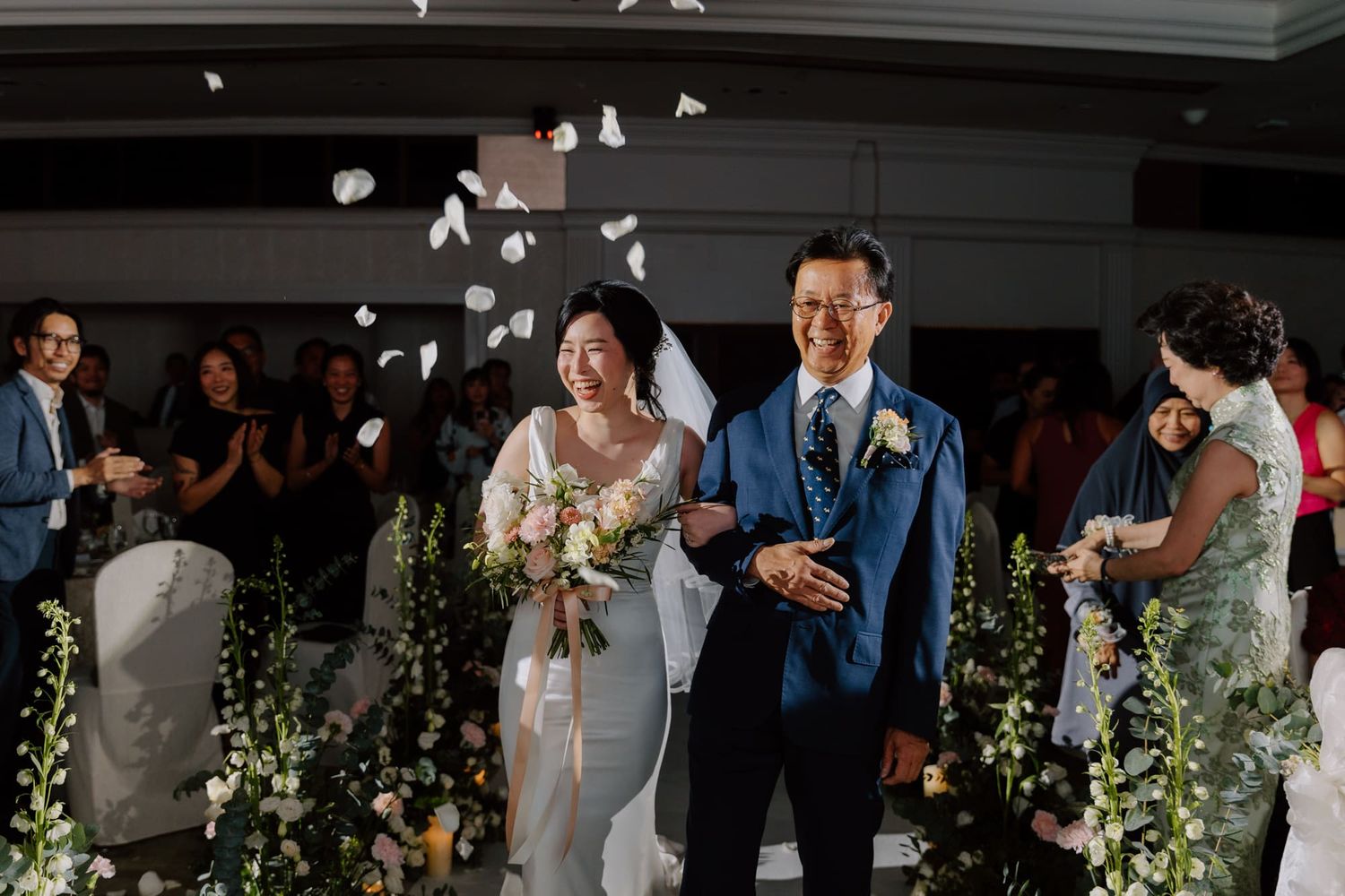 A couple shares a romantic dance together during their wedding reception with floral decorations and guests looking on.