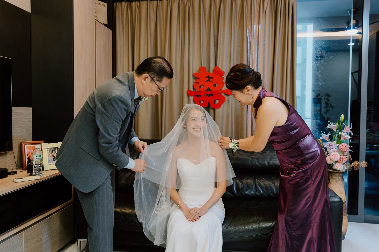 A tender moment during wedding preparation as a veil is being adjusted.