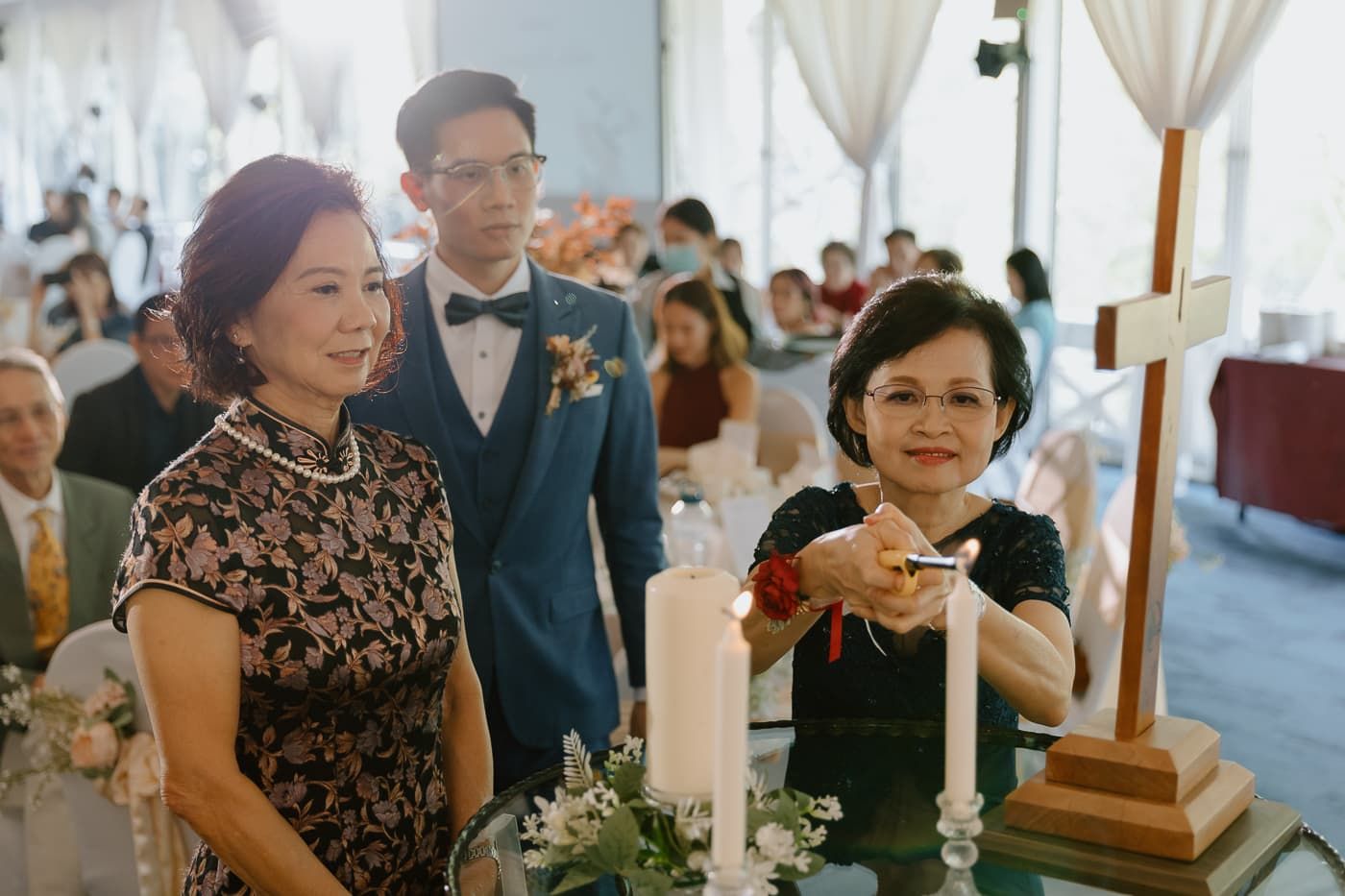 Wedding ceremony attendees gather around candle display during traditional ritual.
