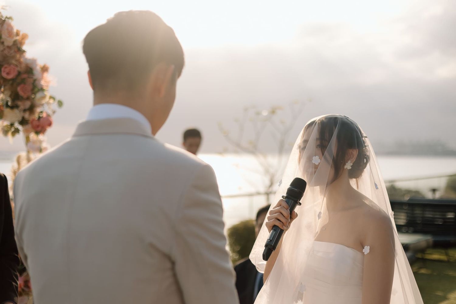 A couple exchanging vows during their sunset wedding ceremony by the ocean.