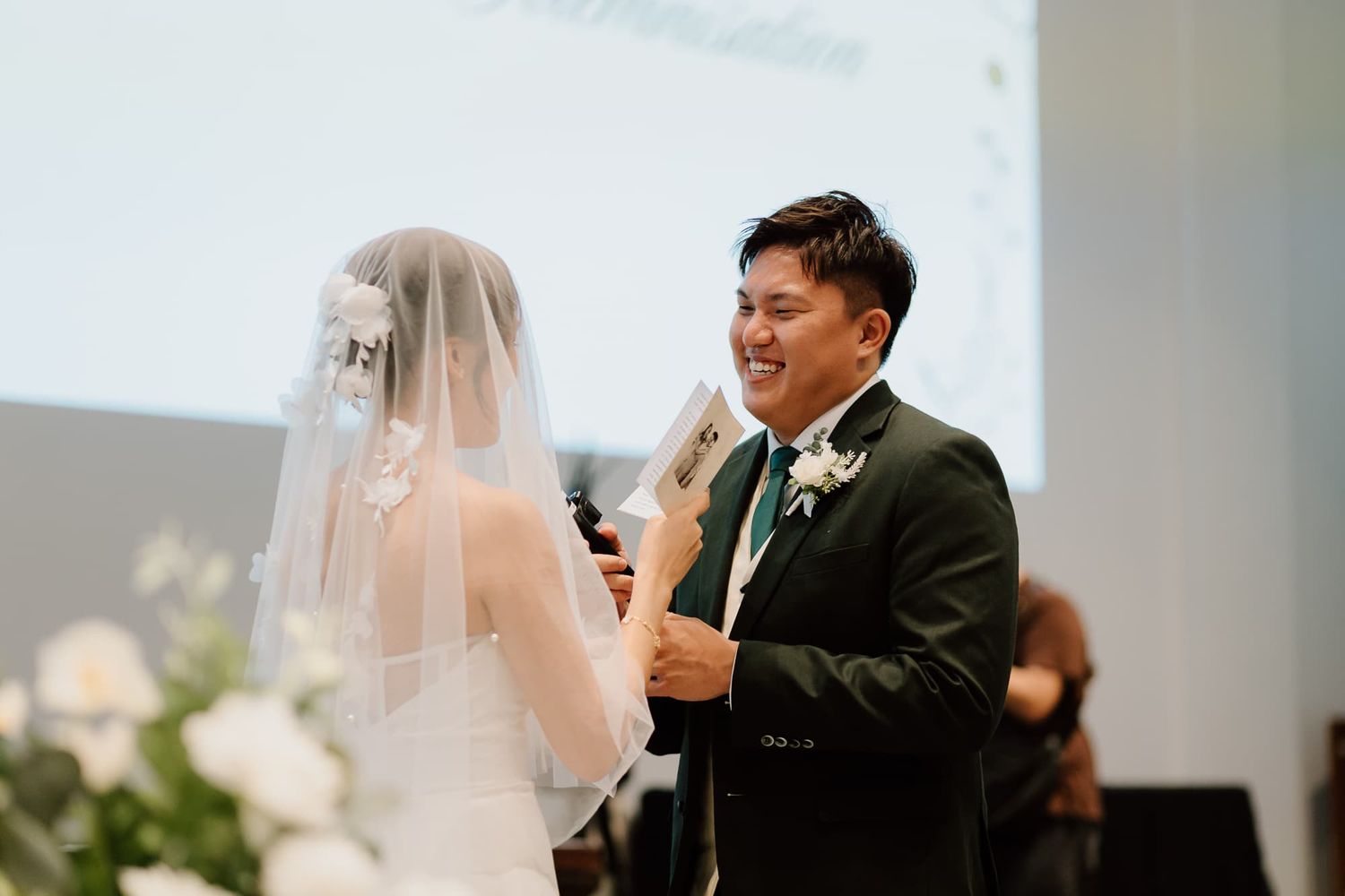 Emotional wedding ceremony taking place in modern church sanctuary with white decor.