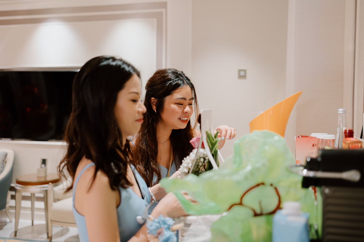 Two people in blue dresses looking at a green painting or artwork.