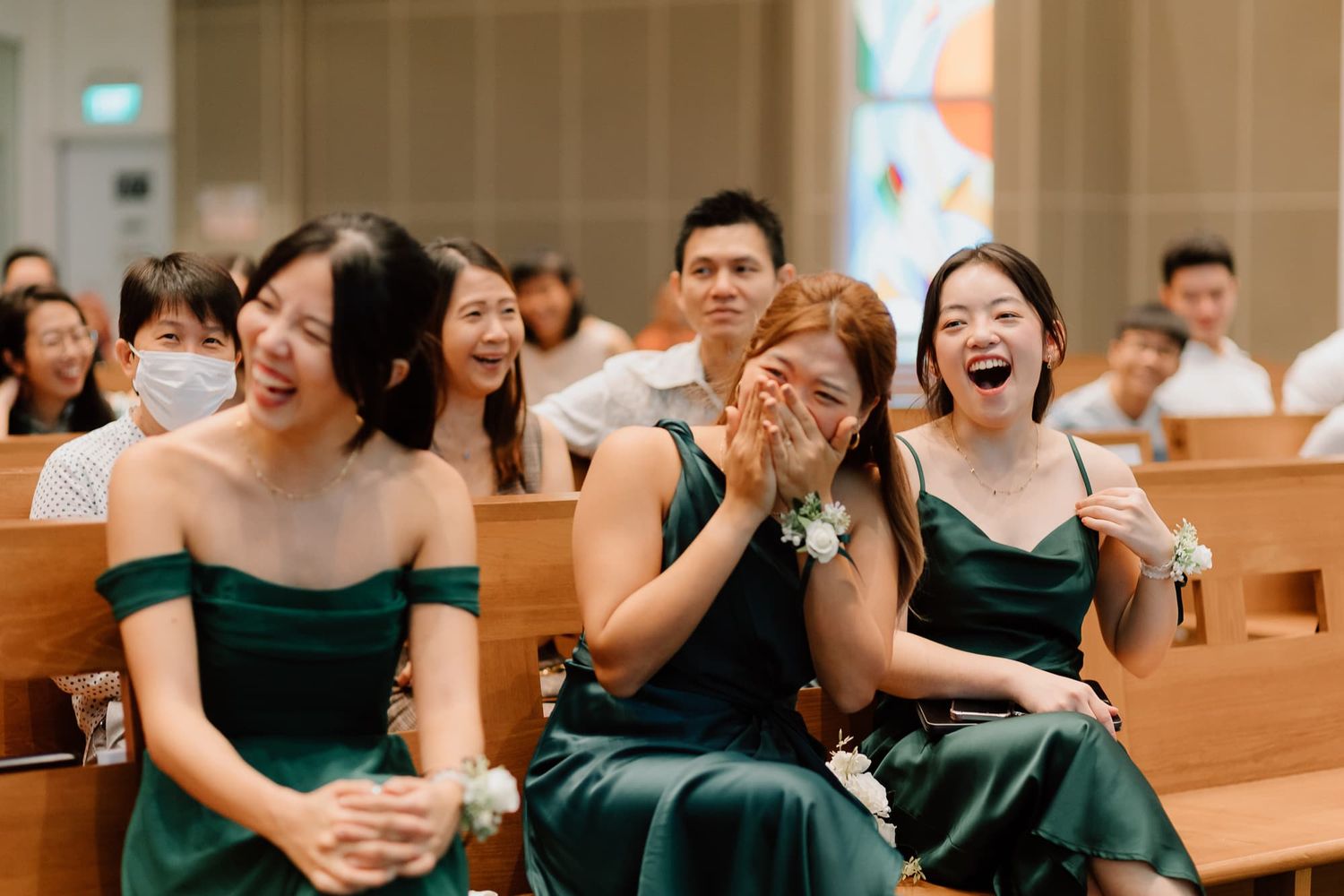 Wedding guests in dark attire sharing joyful moments during the ceremony.