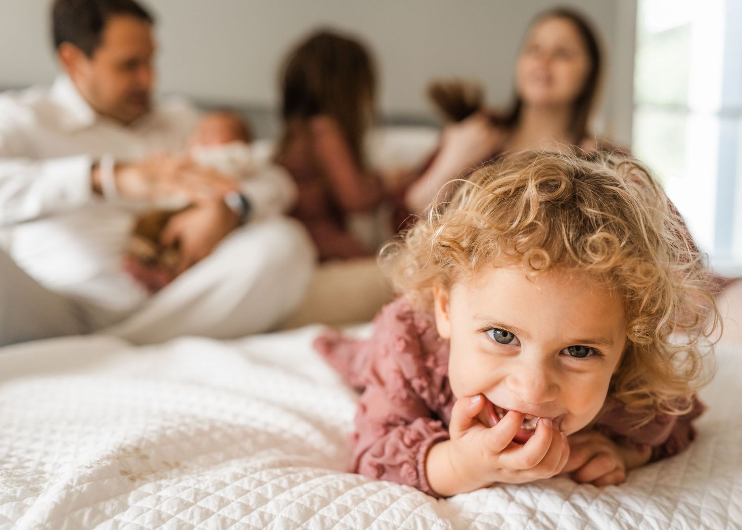 Children and parents sharing playful moment on white bed.