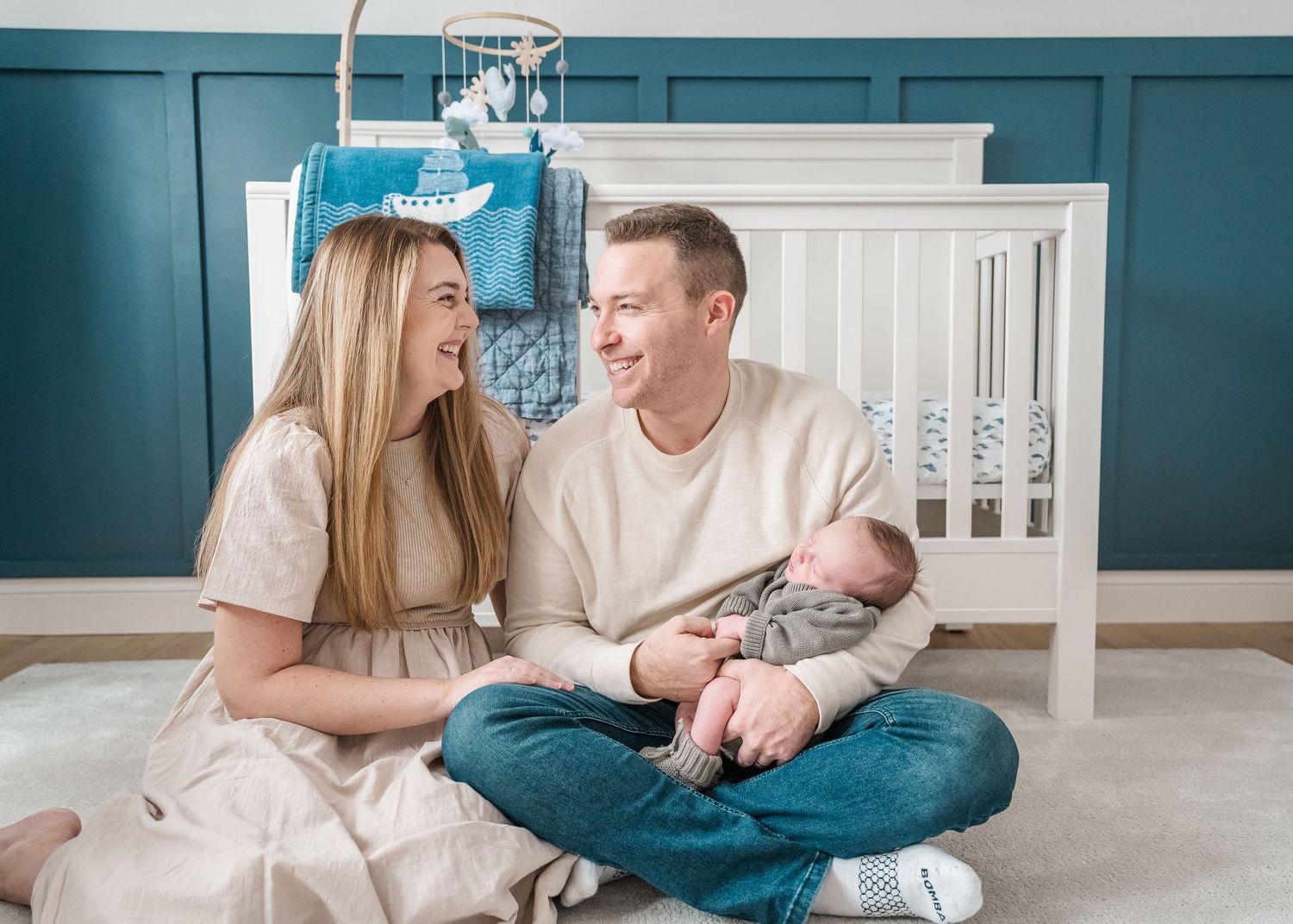 Family lifestyle session showing tender moments on bedroom floor with teal walls.