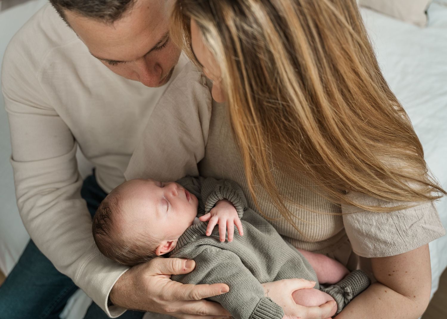 A parent and child share a tender moment while sitting together in matching beige sweaters.