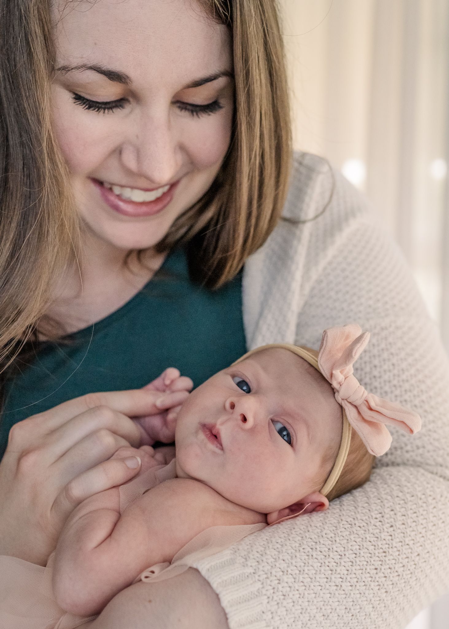 Tender moment between caregiver and baby wearing peach bow headband.