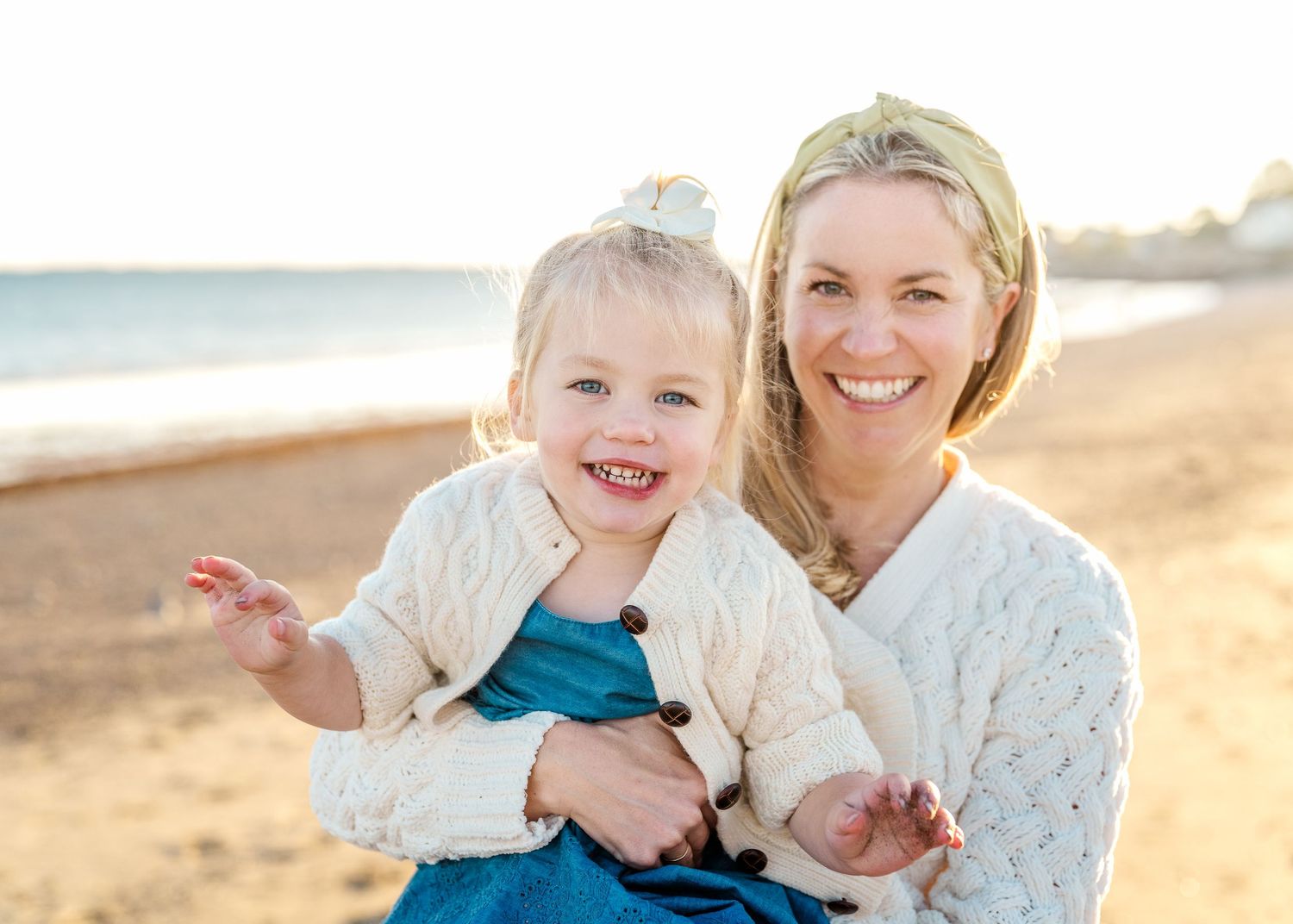 Joyful beach portrait of mother and child laughing together in warm sunlight.