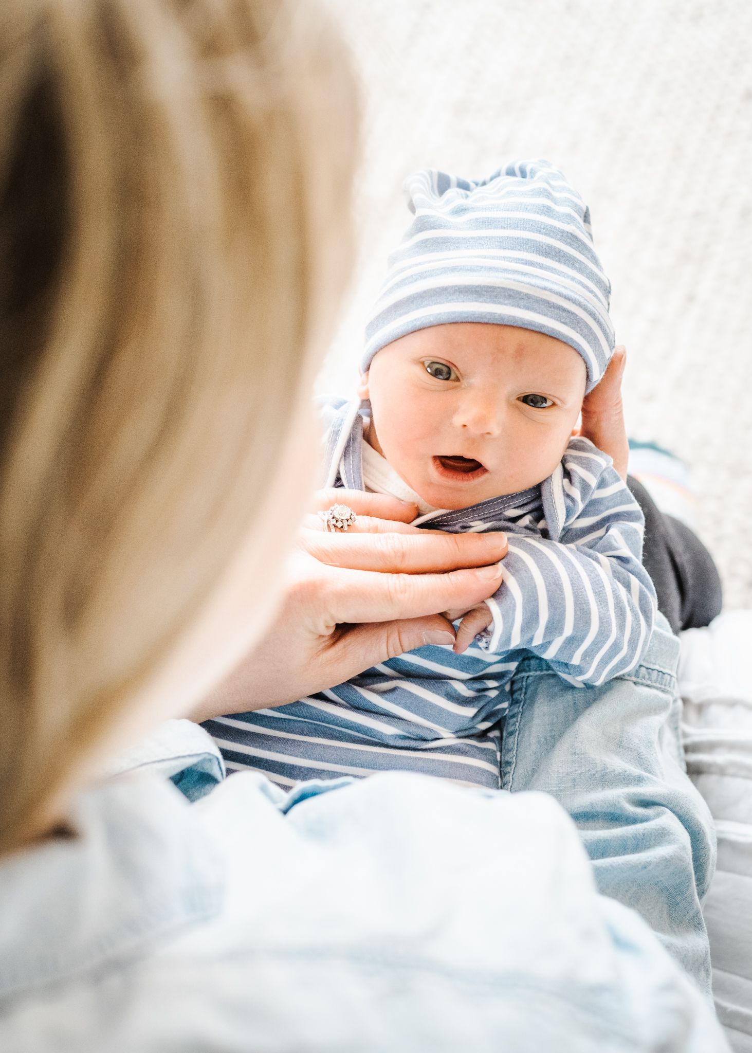 Alert baby in striped outfit and matching hat looking up with wonder.