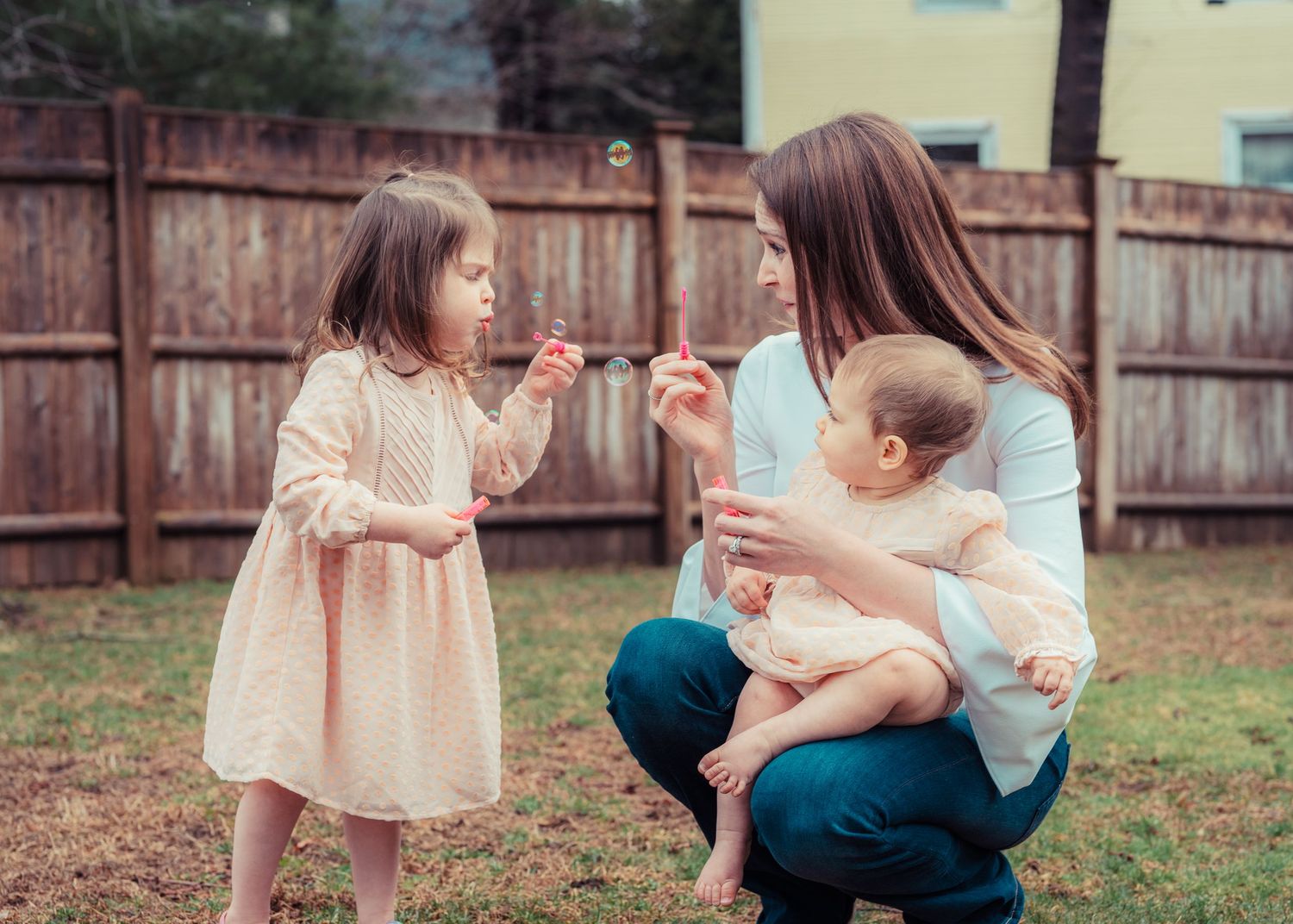 A playful outdoor moment between family members in a backyard setting.