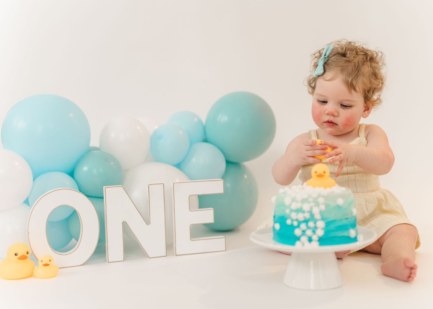 Cake smash. Baby milestone photo collage with teal decorations showing monthly growth progression from newborn to one year old.