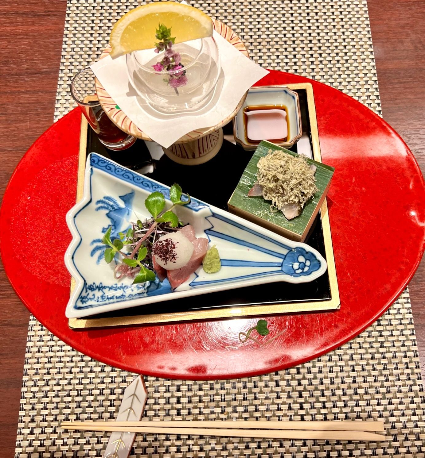 Elegant Japanese dishes arranged on a red lacquer plate with traditional ceramic serving pieces.