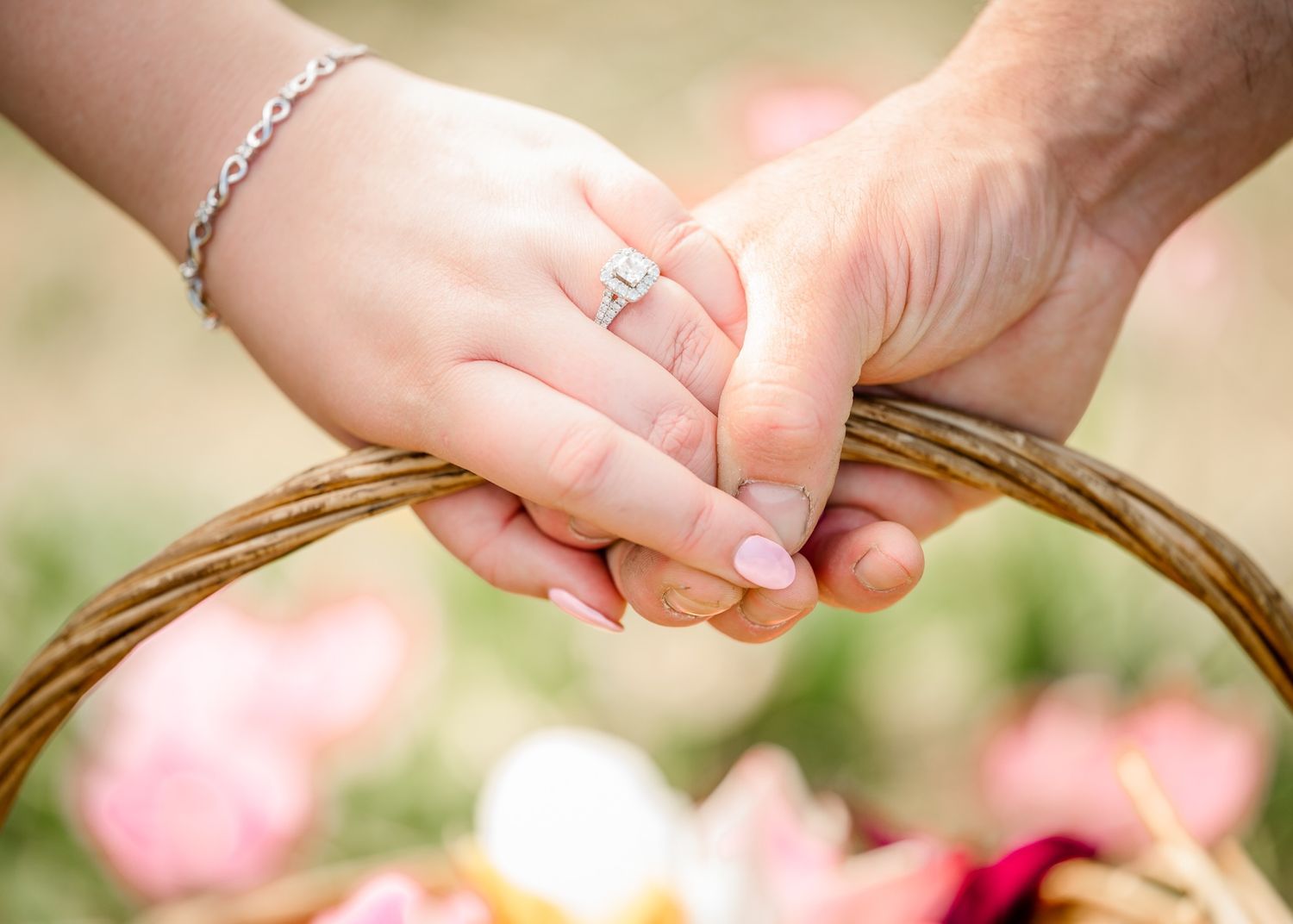 Close up of hands with engagement ring holding wicker basket handle.
