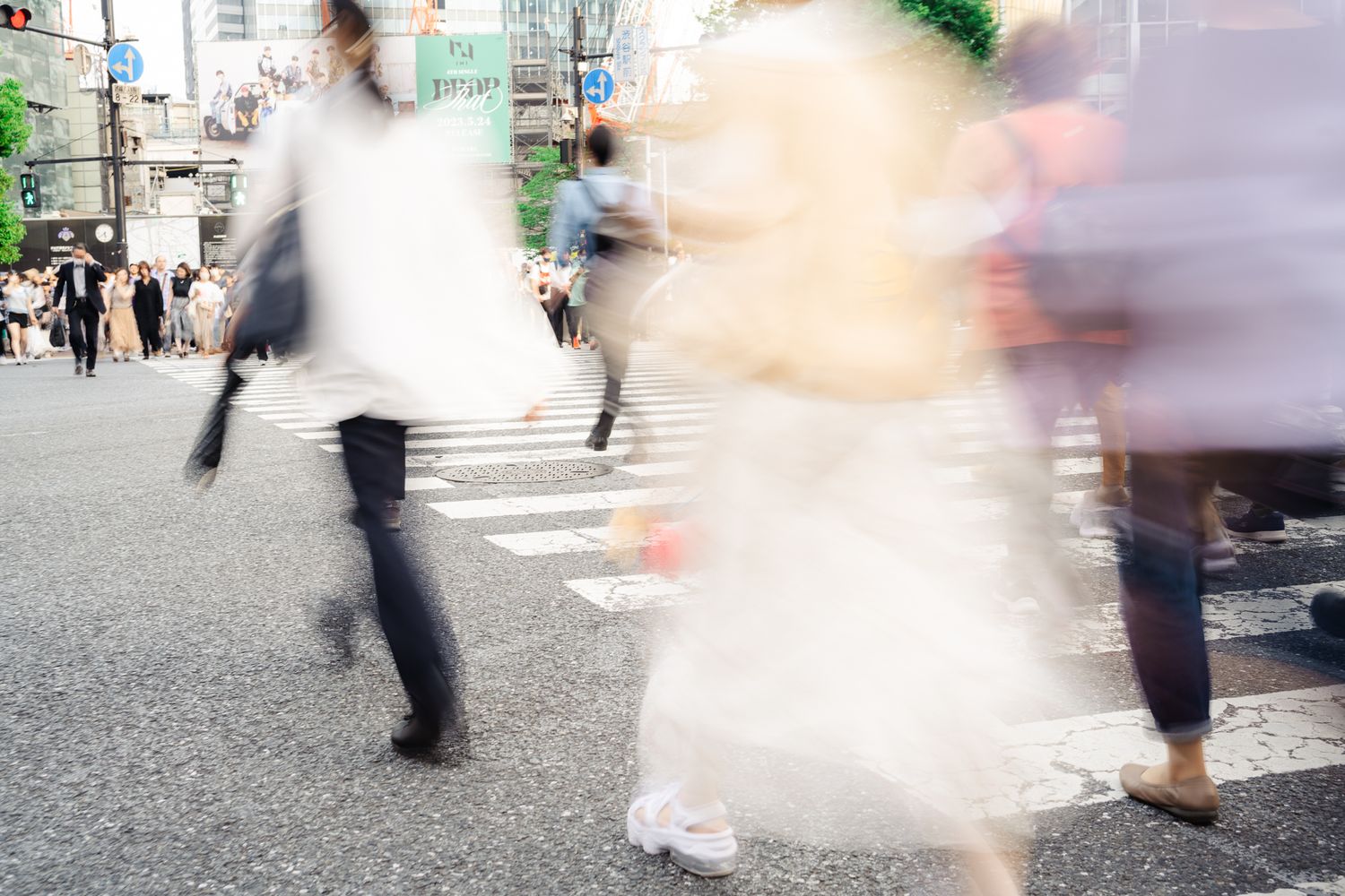 Motion-blurred pedestrians crossing an urban intersection in soft lighting.