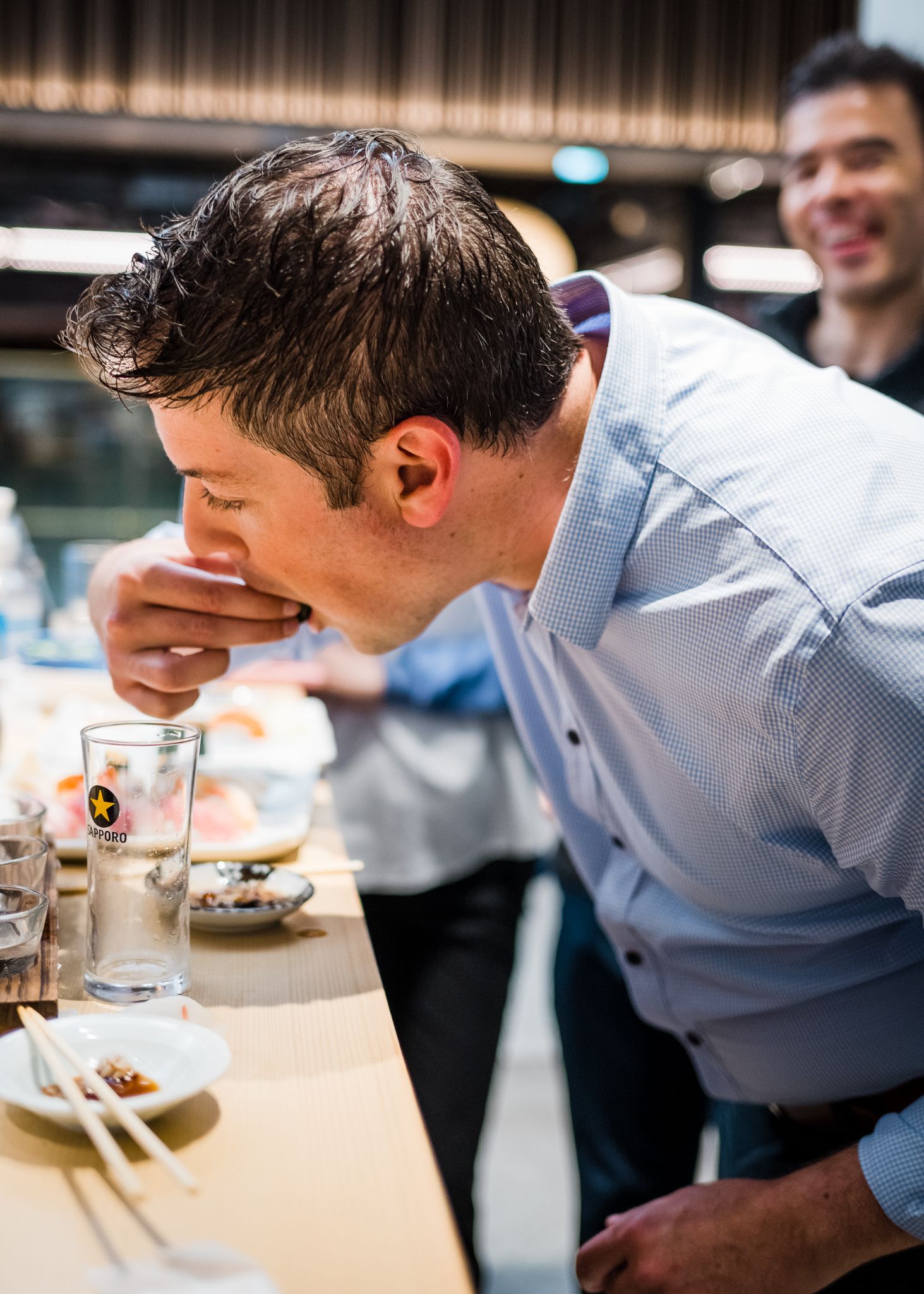Person in business attire taking a bite of food at a restaurant table.
