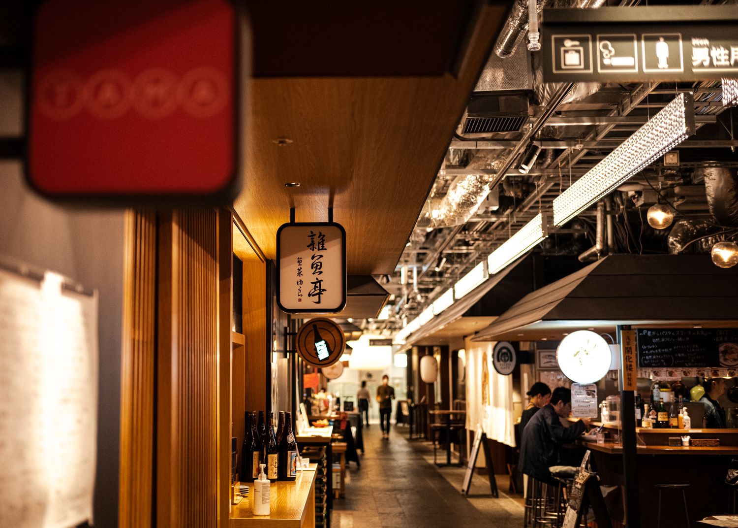 Traditional Japanese restaurant corridor with hanging lanterns and warm lighting.