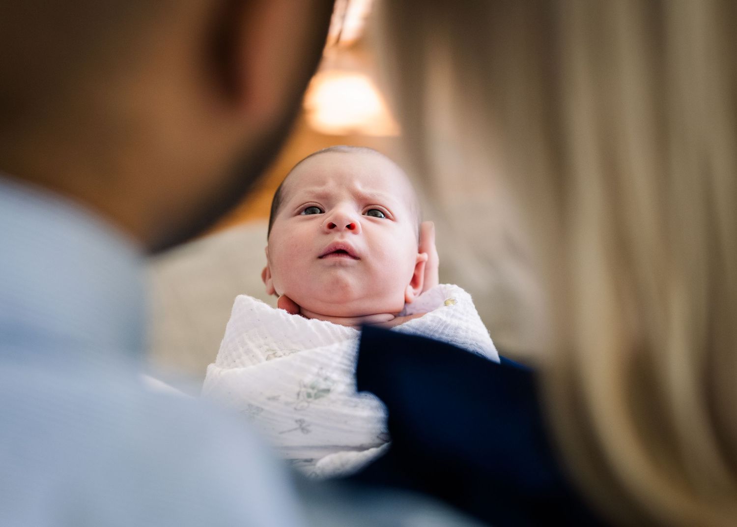 Close up view of newborn baby wrapped in white blanket.