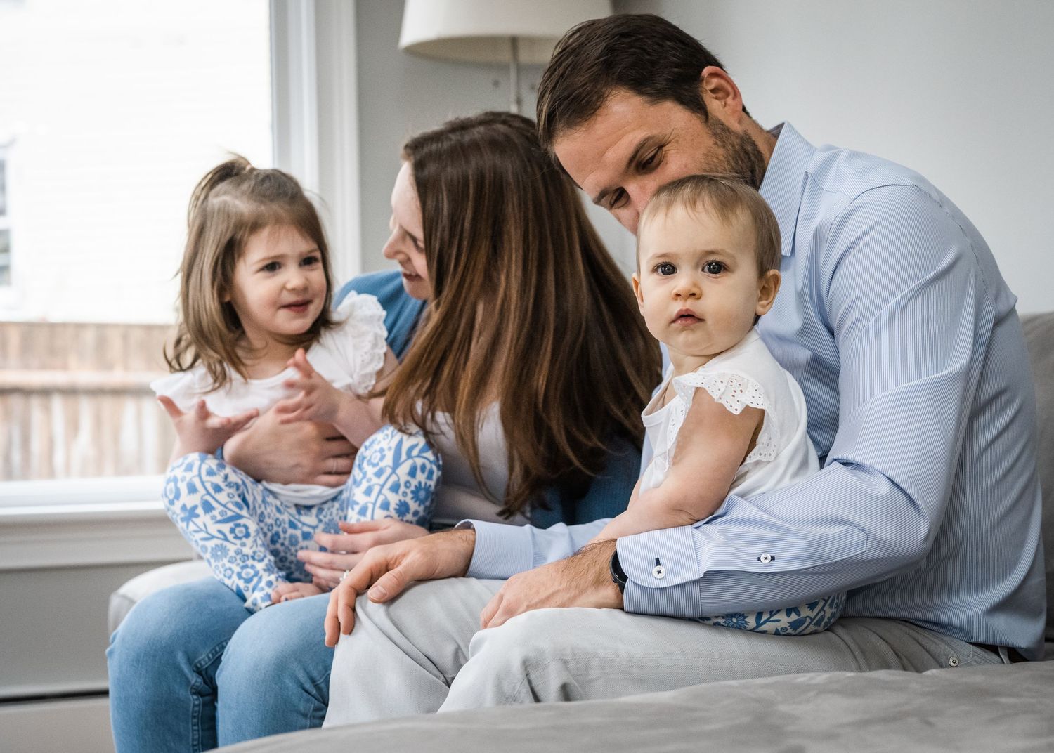 Family sitting together on couch in coordinated blue and white outfits.