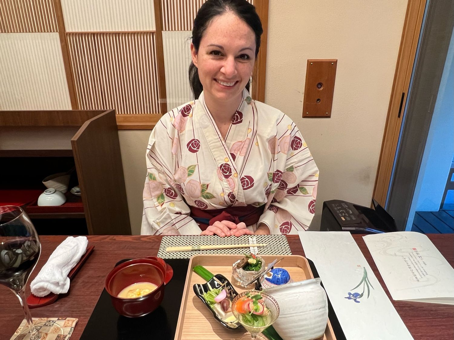 A traditional Japanese dining setup with sushi and appetizers on a decorative red plate.