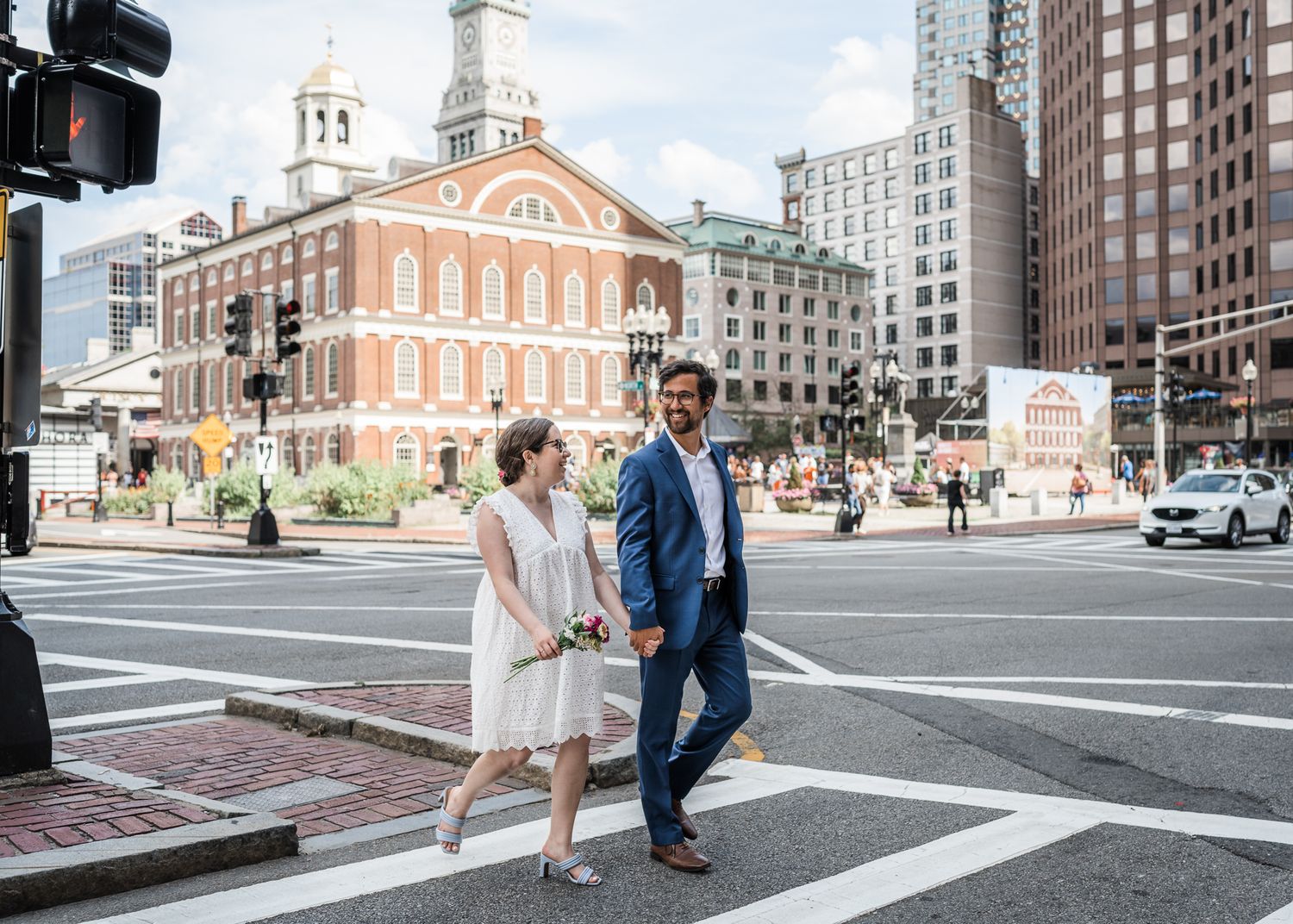 A couple walks hand in hand past historic Faneuil Hall in downtown Boston.