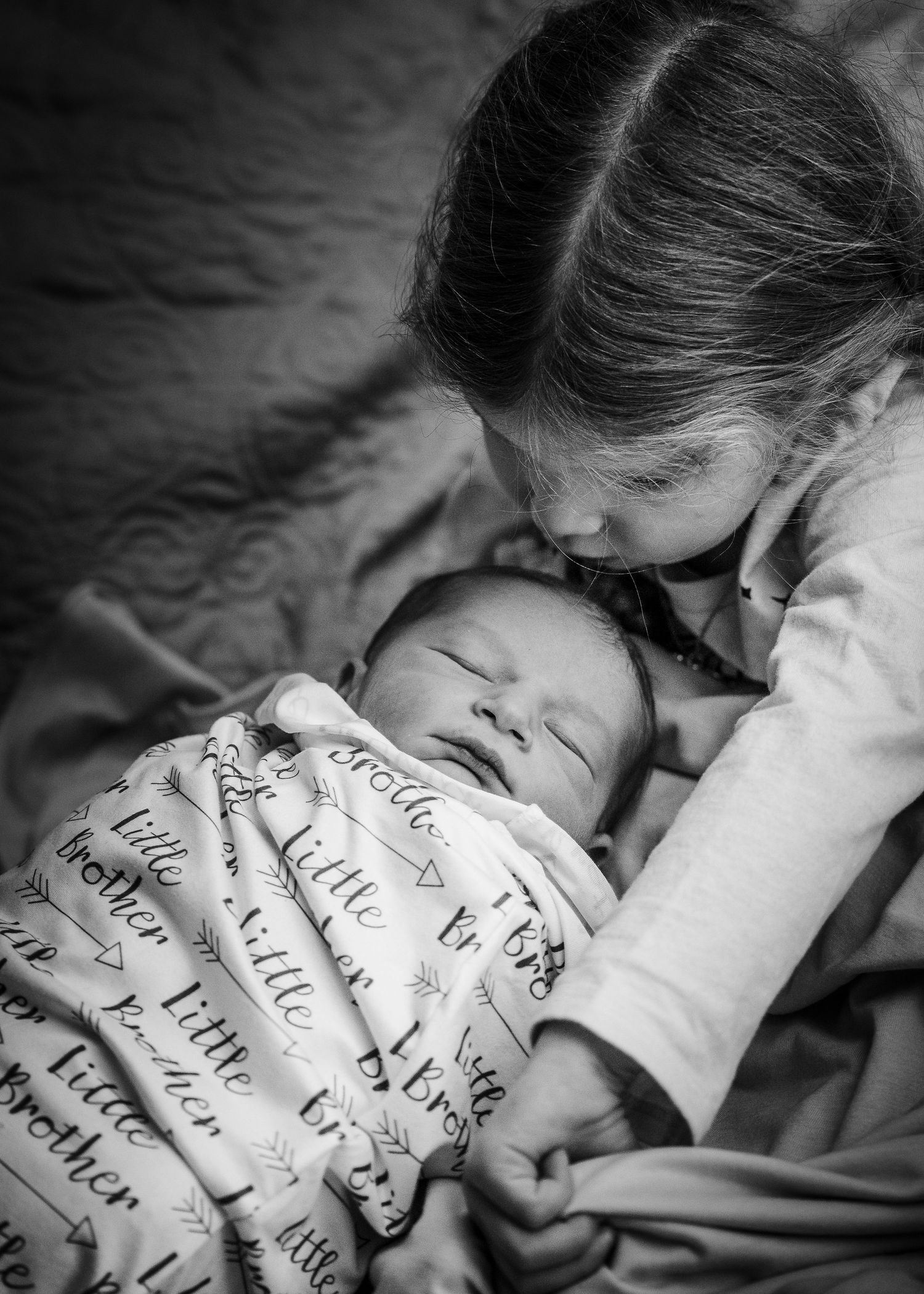 Tender moment between siblings with custom personalized blanket in black and white.