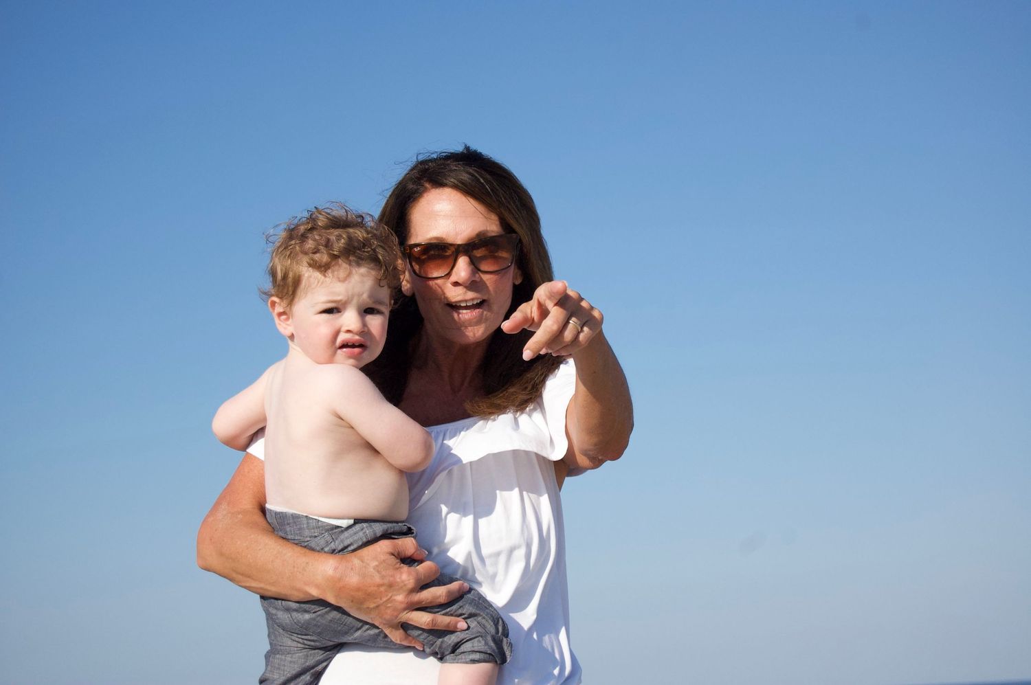 Mother and toddler enjoying a sunny day outdoors against clear blue sky.
