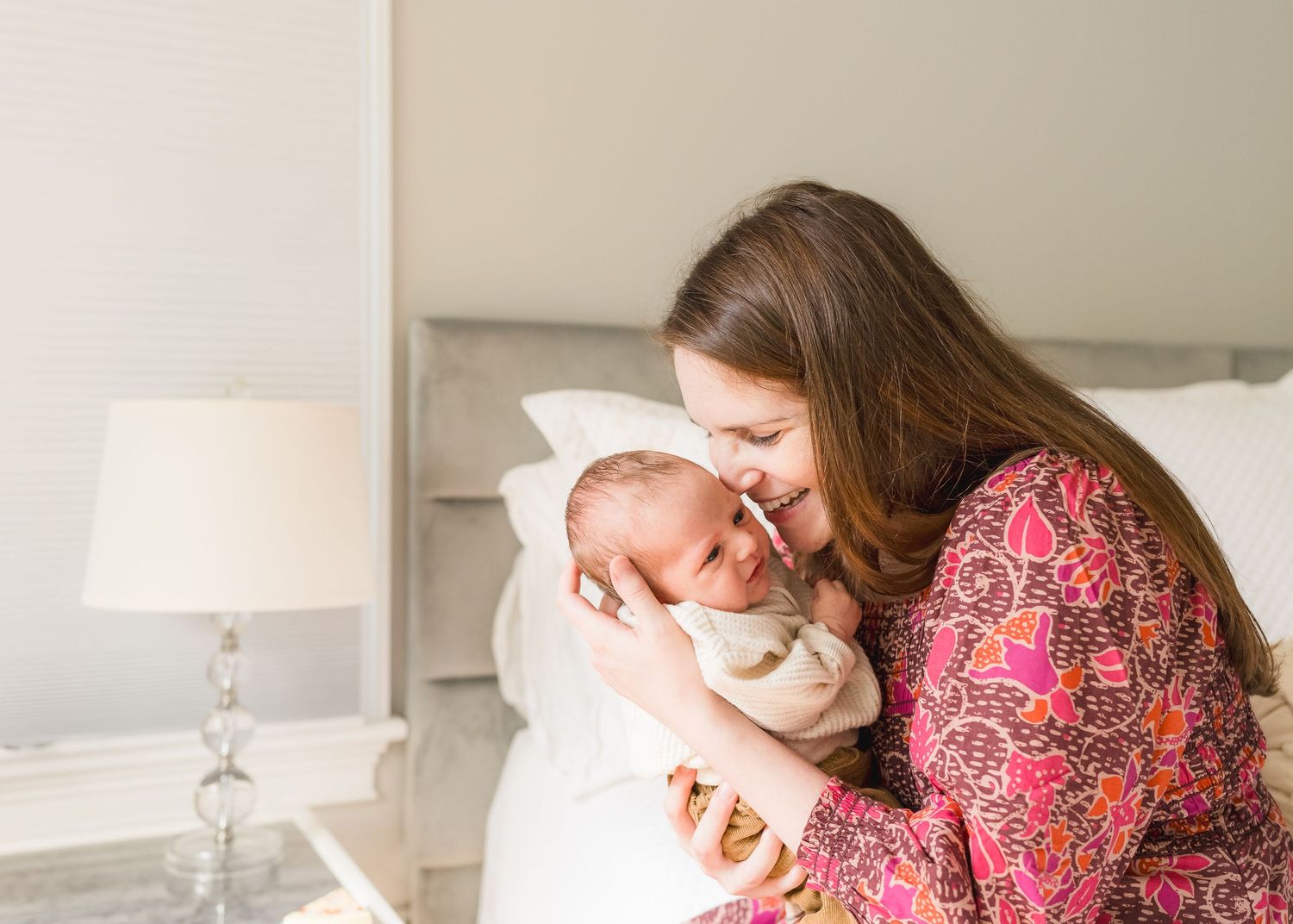Tender moment between mother and newborn baby wrapped in white blanket.