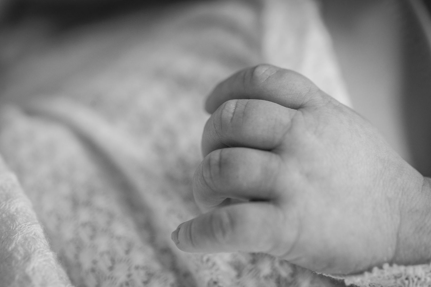 Black and white photo series showing a baby's tiny hand grasping an adult's finger in different tender moments.