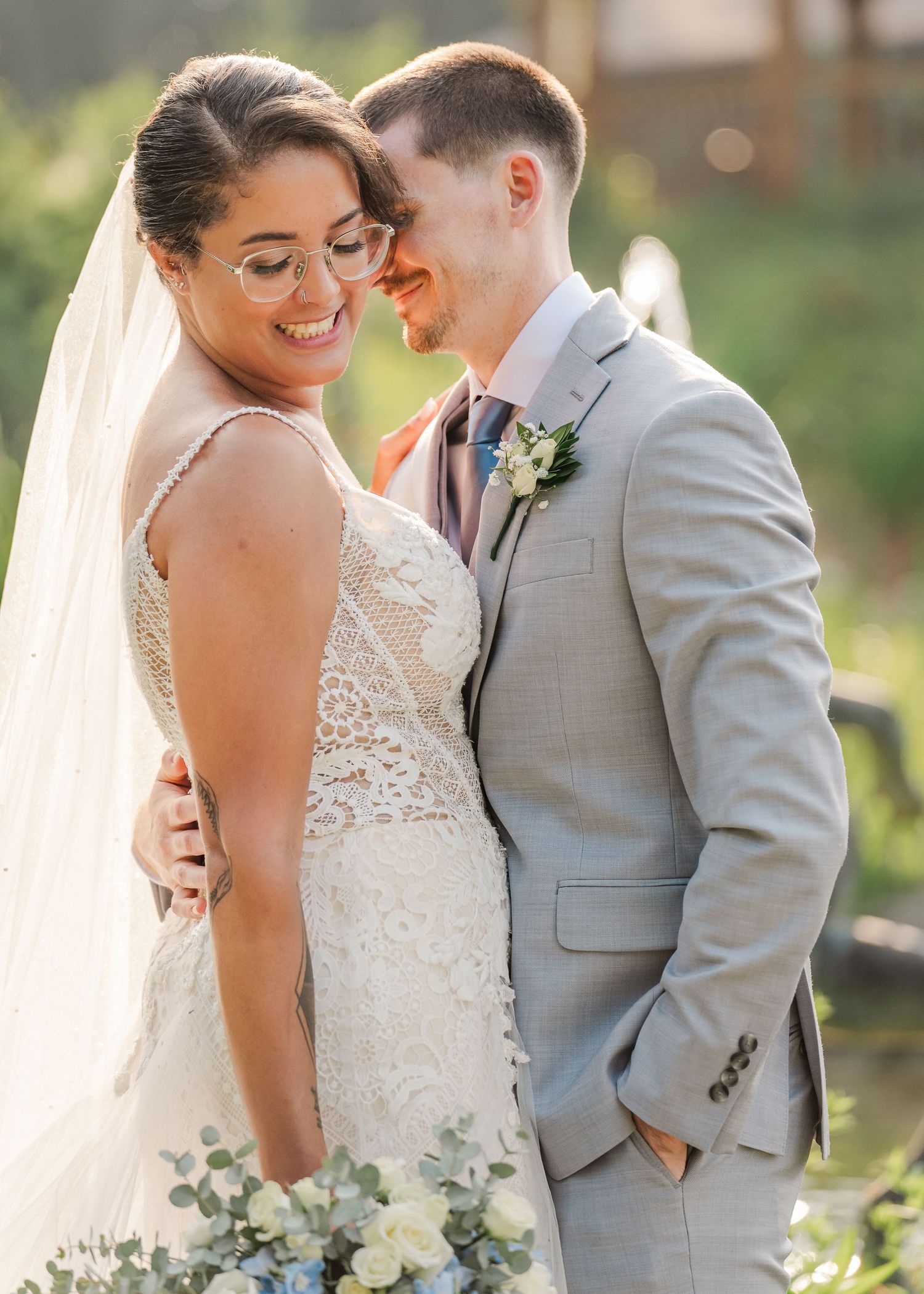A romantic wedding couple shares an intimate moment in a garden setting, surrounded by natural sunlight and greenery.