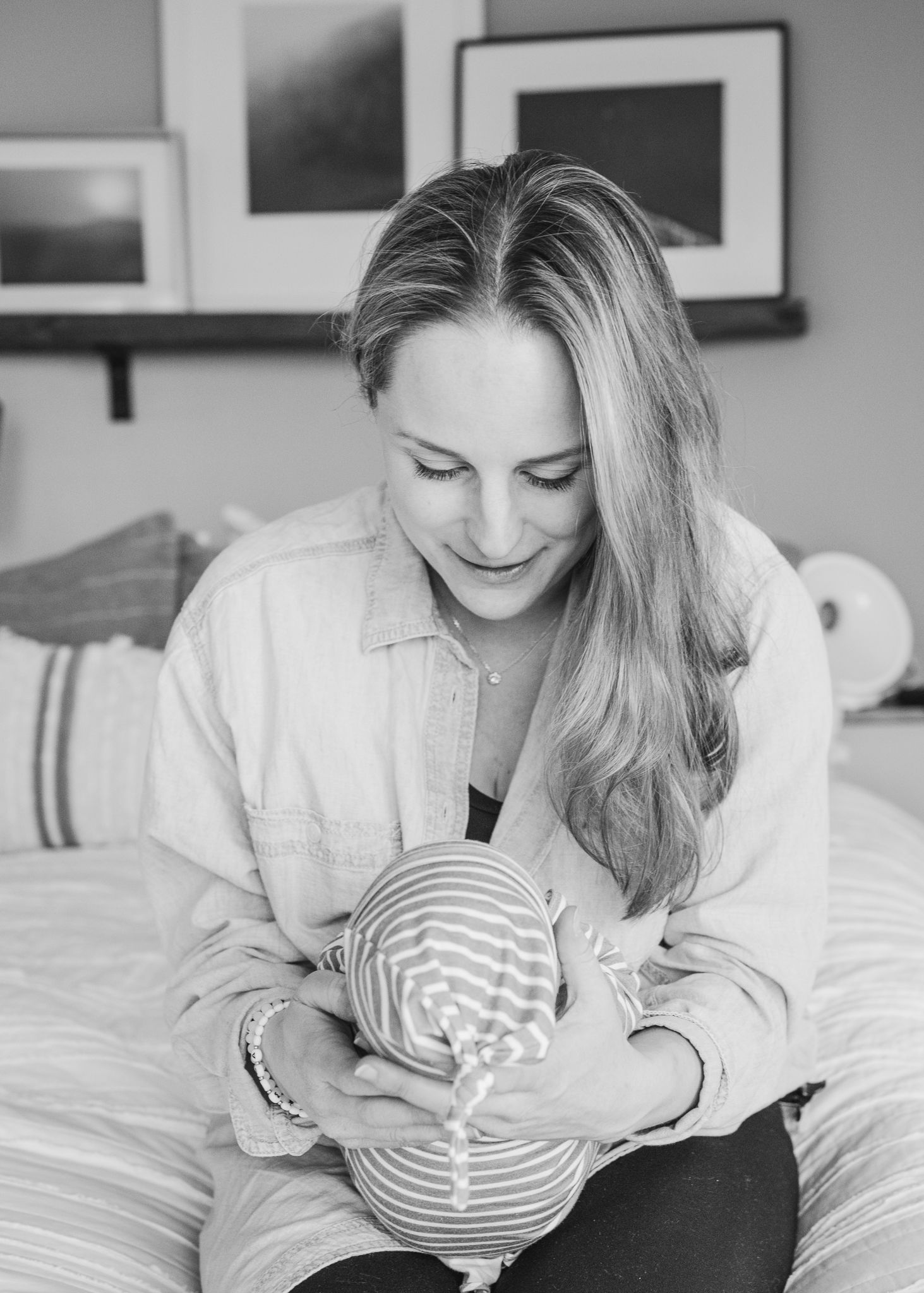 Black and white portrait of tender moment with sleeping infant in stripes.