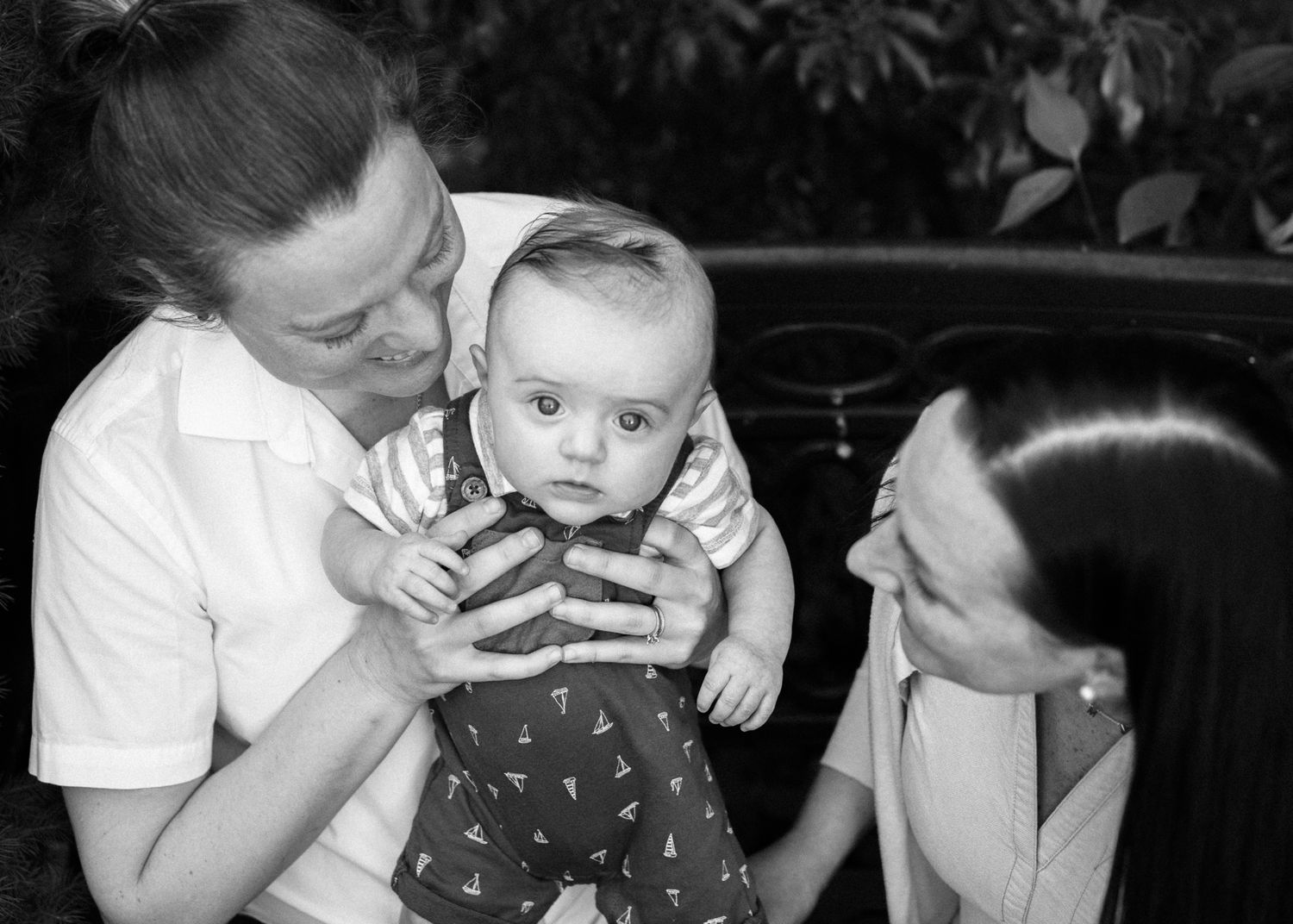 A black and white portrait of a family sharing joy with their small baby.
