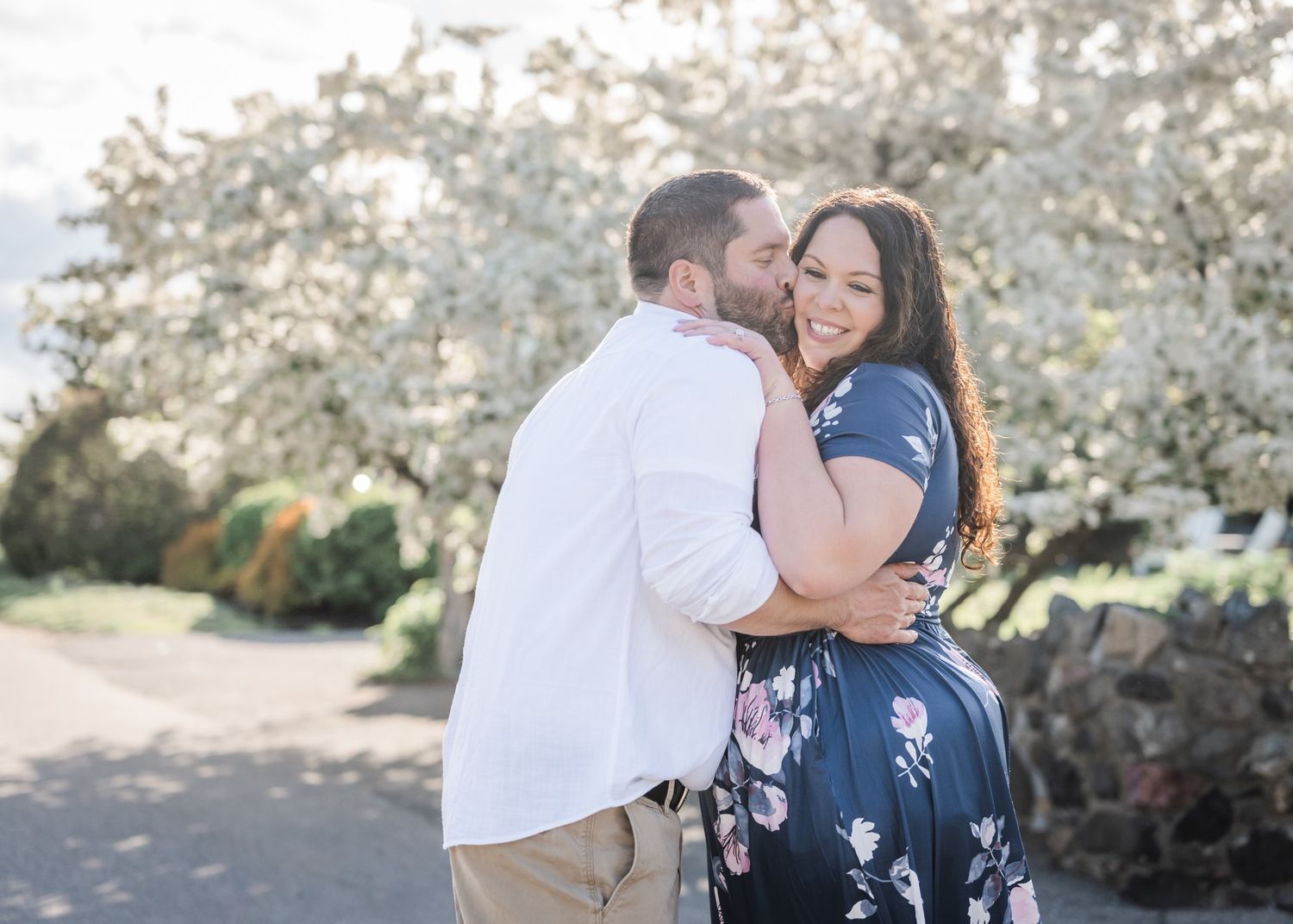 A tender moment between a couple posing among spring blossoms.