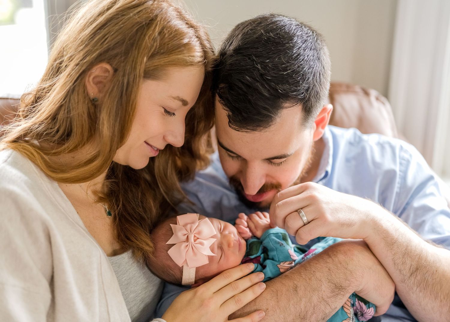 Parents sharing an intimate moment with their newborn baby wrapped in turquoise swaddle.