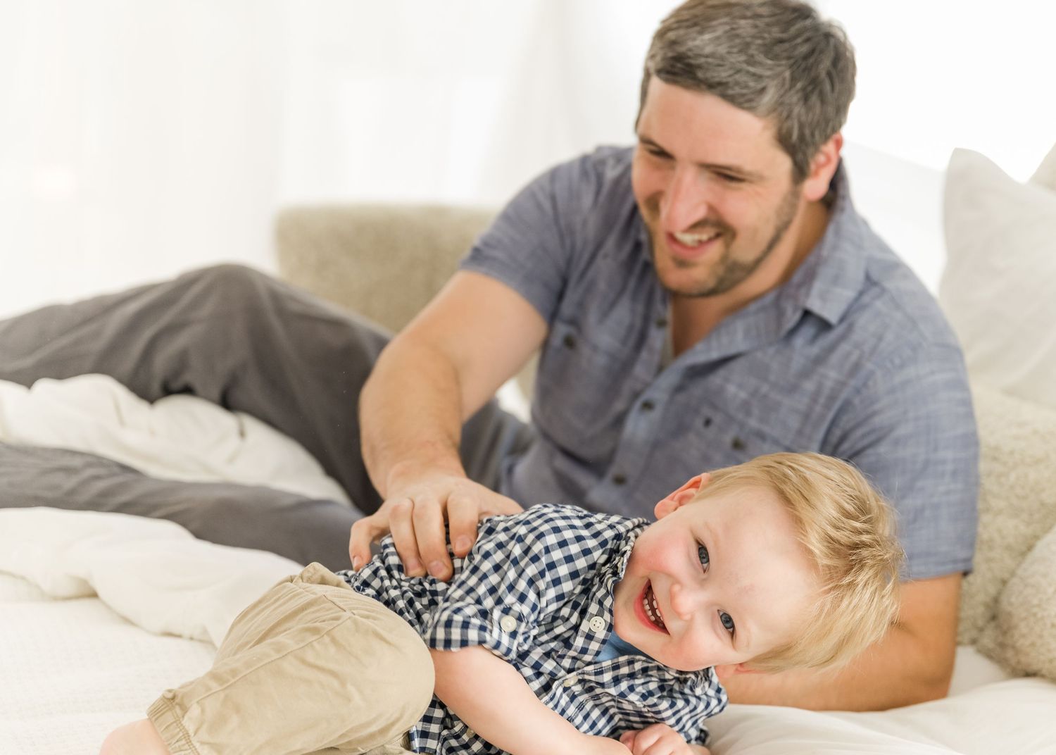 A joyful parent and child sharing a playful moment while lying on a bed together.