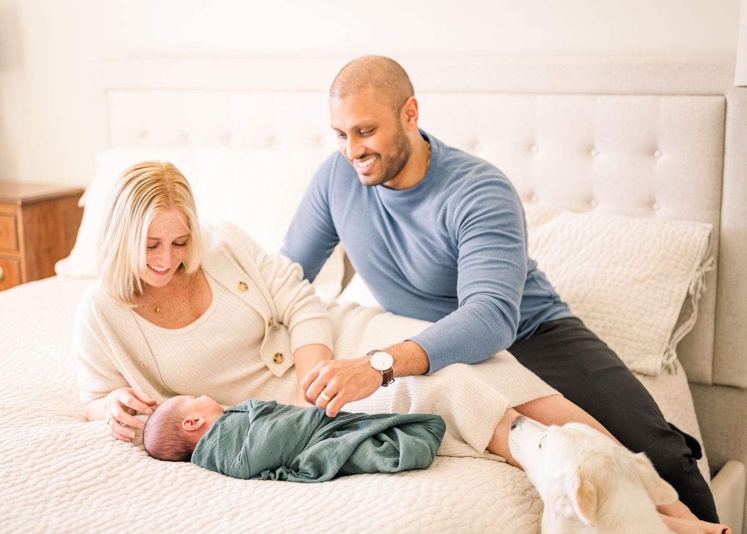 Family sharing a tender moment together on white bed.