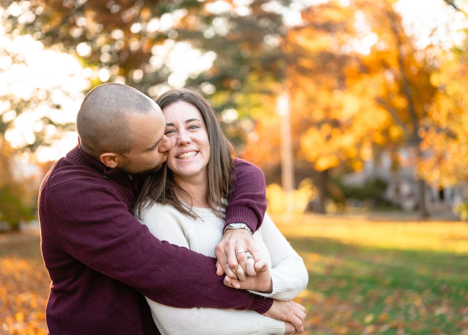 A loving embrace captured during a fall photo session with golden leaves in the background.