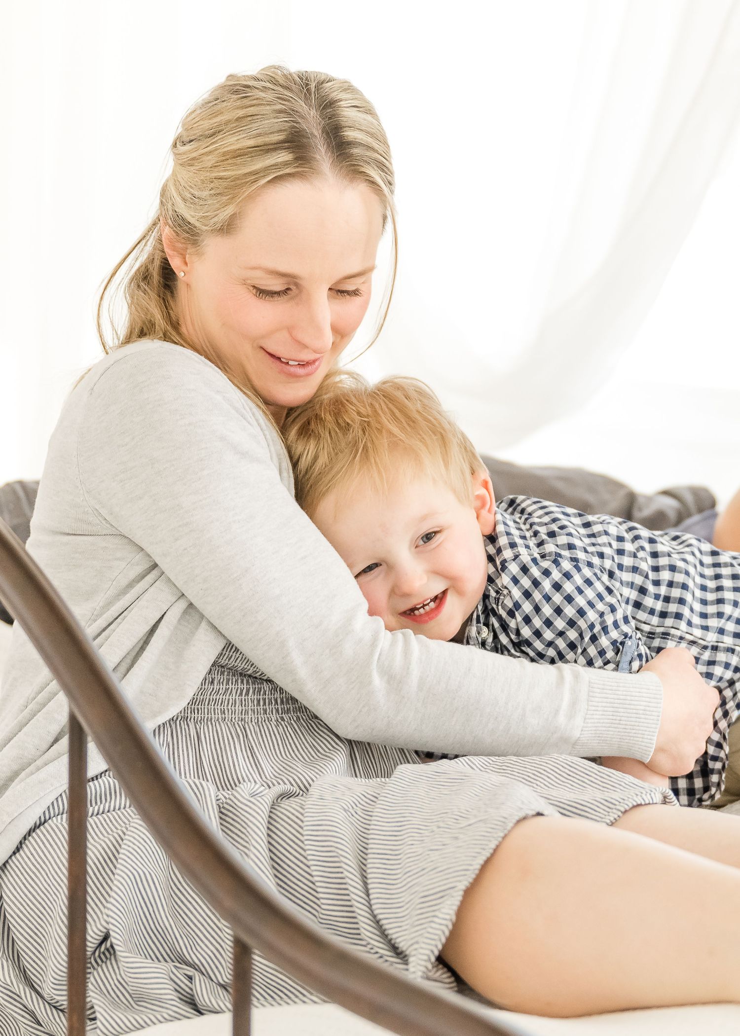 A parent and child share a joyful moment while cuddling together on a comfortable chair.
