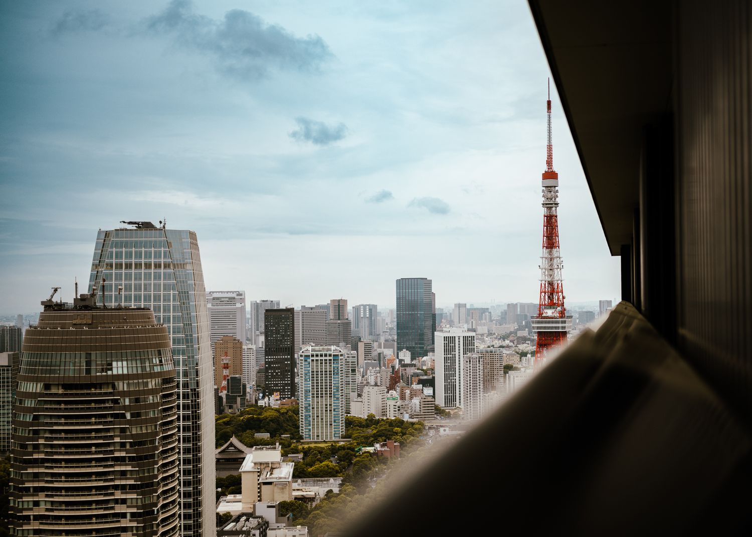 View of Tokyo Tower and surrounding buildings during blue hour from high vantage point.