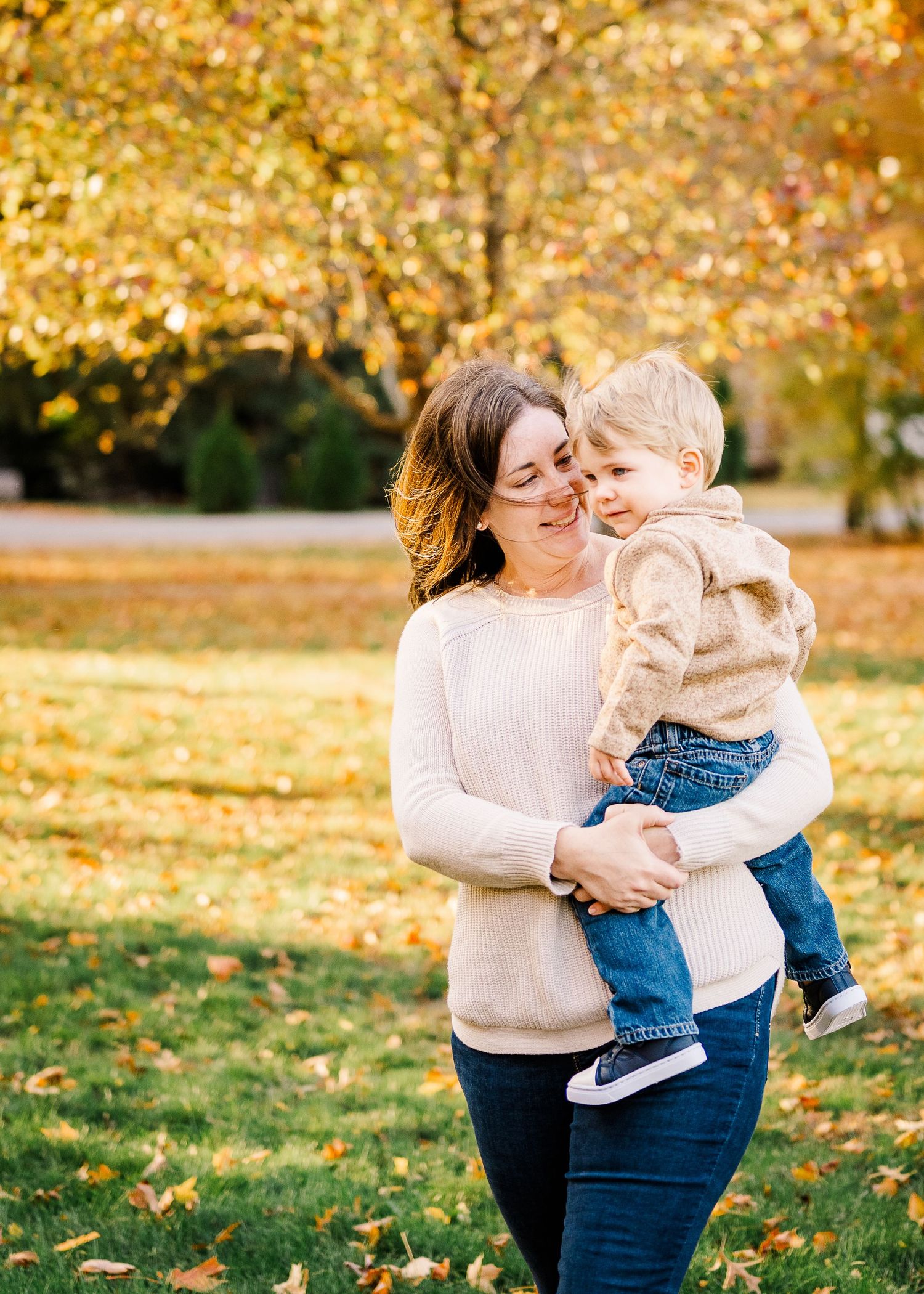 Tender moment between parent and child amid golden fall foliage outdoors.