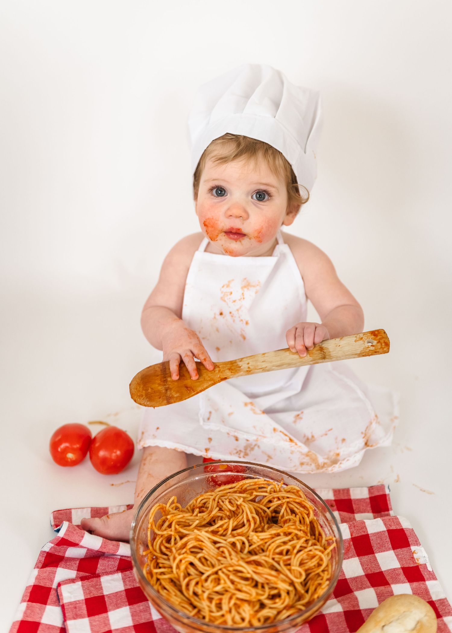 Spaghetti Smash first birthday. A messy spaghetti dinner scene with red and white checkered tablecloth and fresh tomatoes.