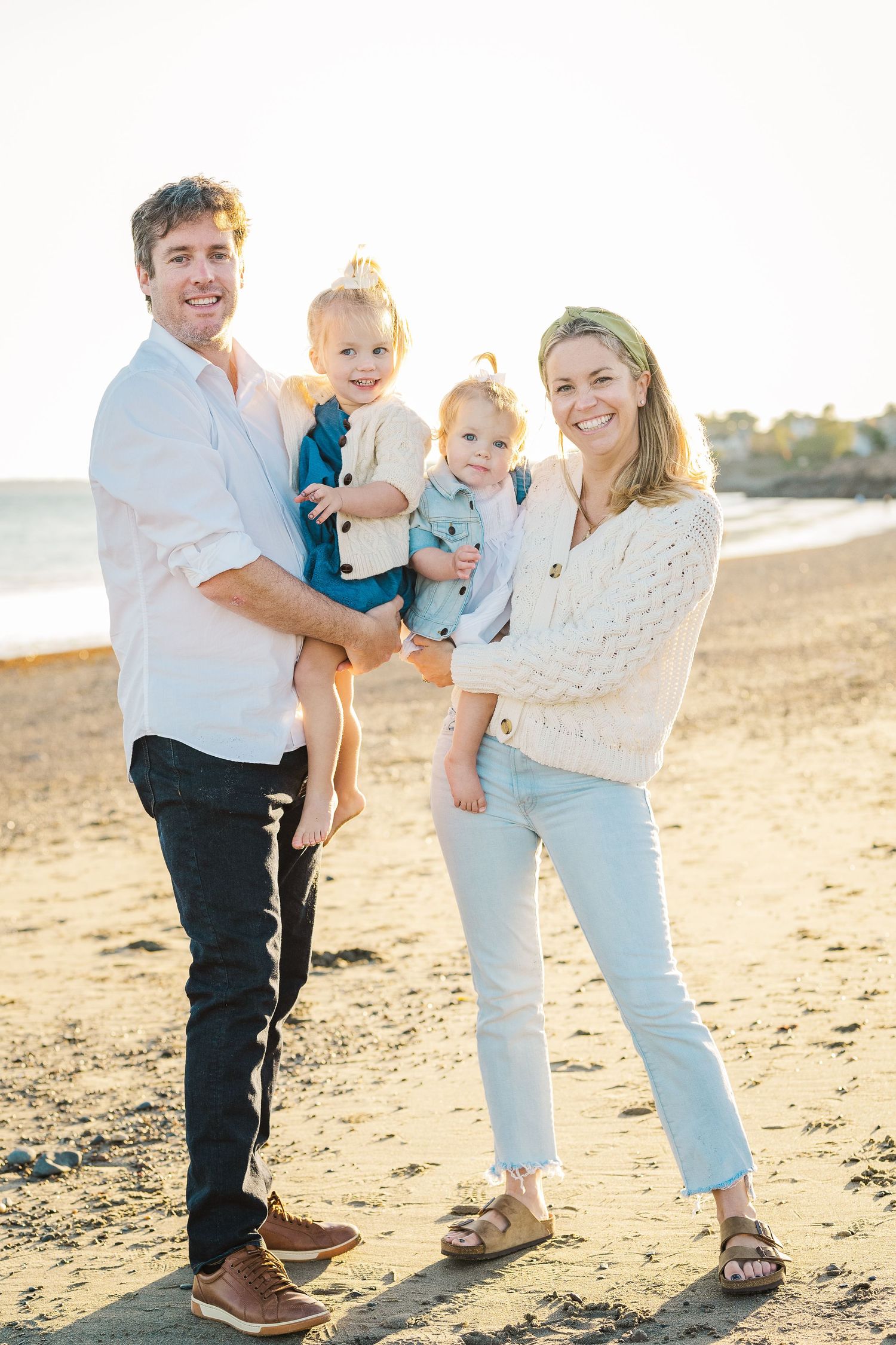 Family portrait at beach with everyone dressed in coordinating blue and white outfits.