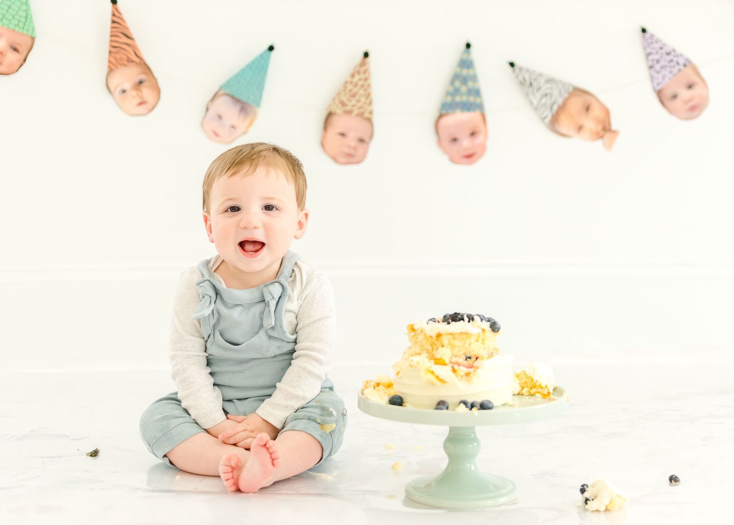 First birthday celebration setup with white and peach decorations featuring a cake on a mint green pedestal stand.