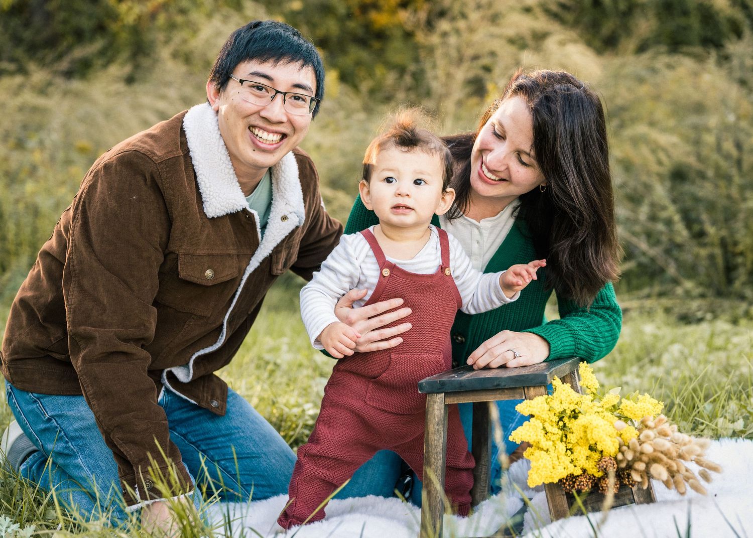 Family outdoor photo session with rustic decorations and yellow flowers against natural foliage.